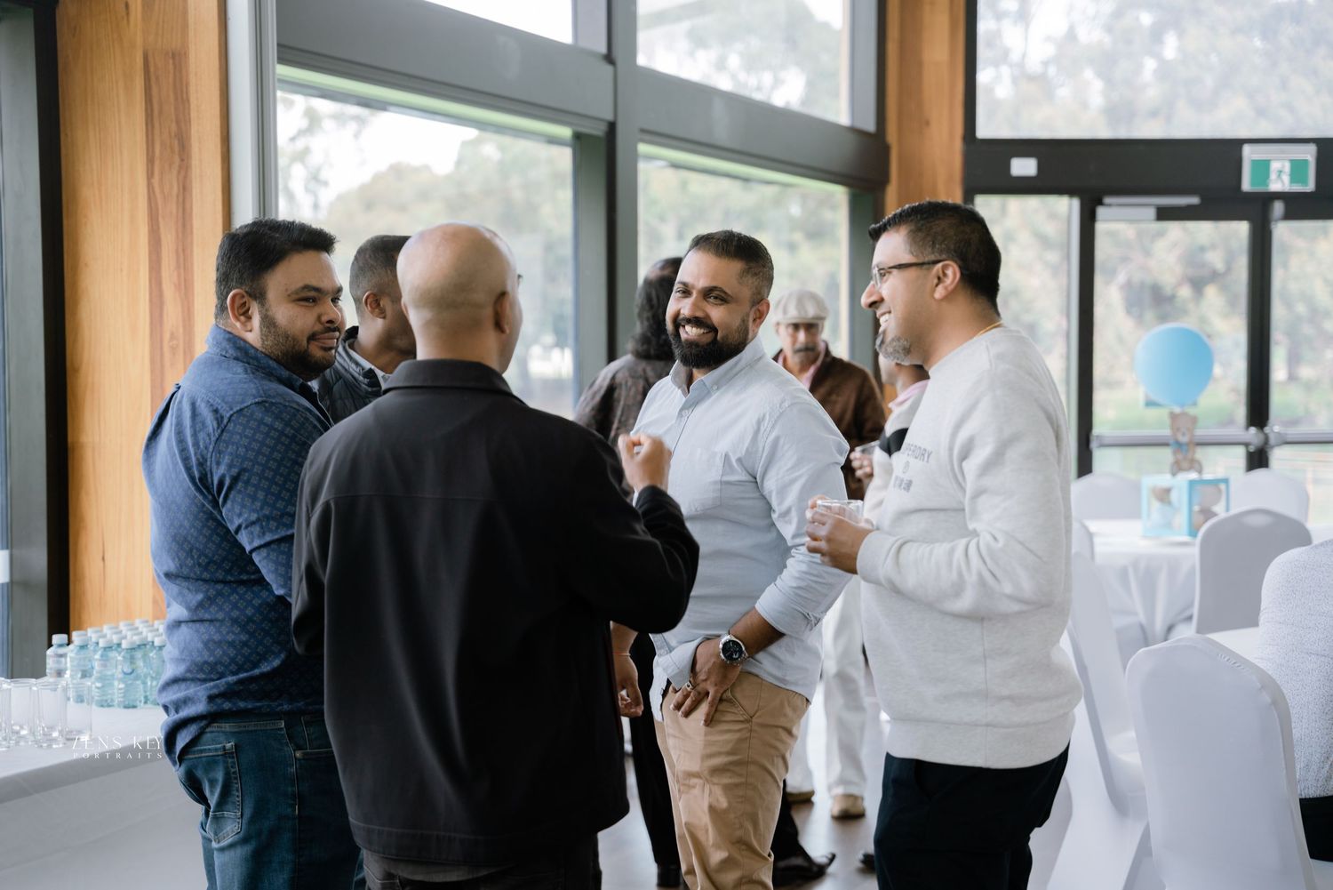 Group of men networking and conversing at an indoor event venue.