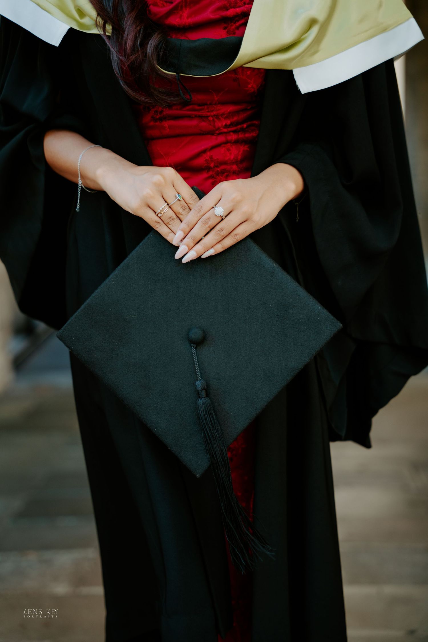 Close-up of graduate holding black mortarboard cap with tassel while wearing academic gown.