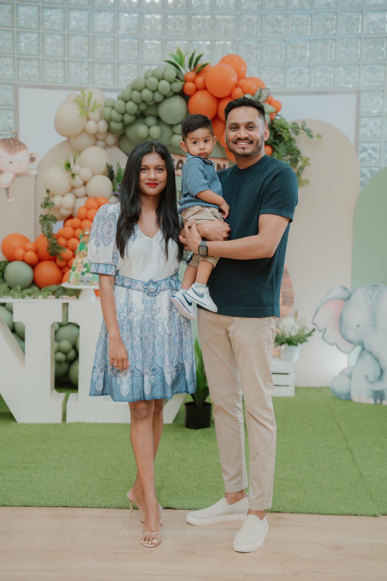 Young family poses together at a Wild One safari-themed first birthday party with balloon backdrop.