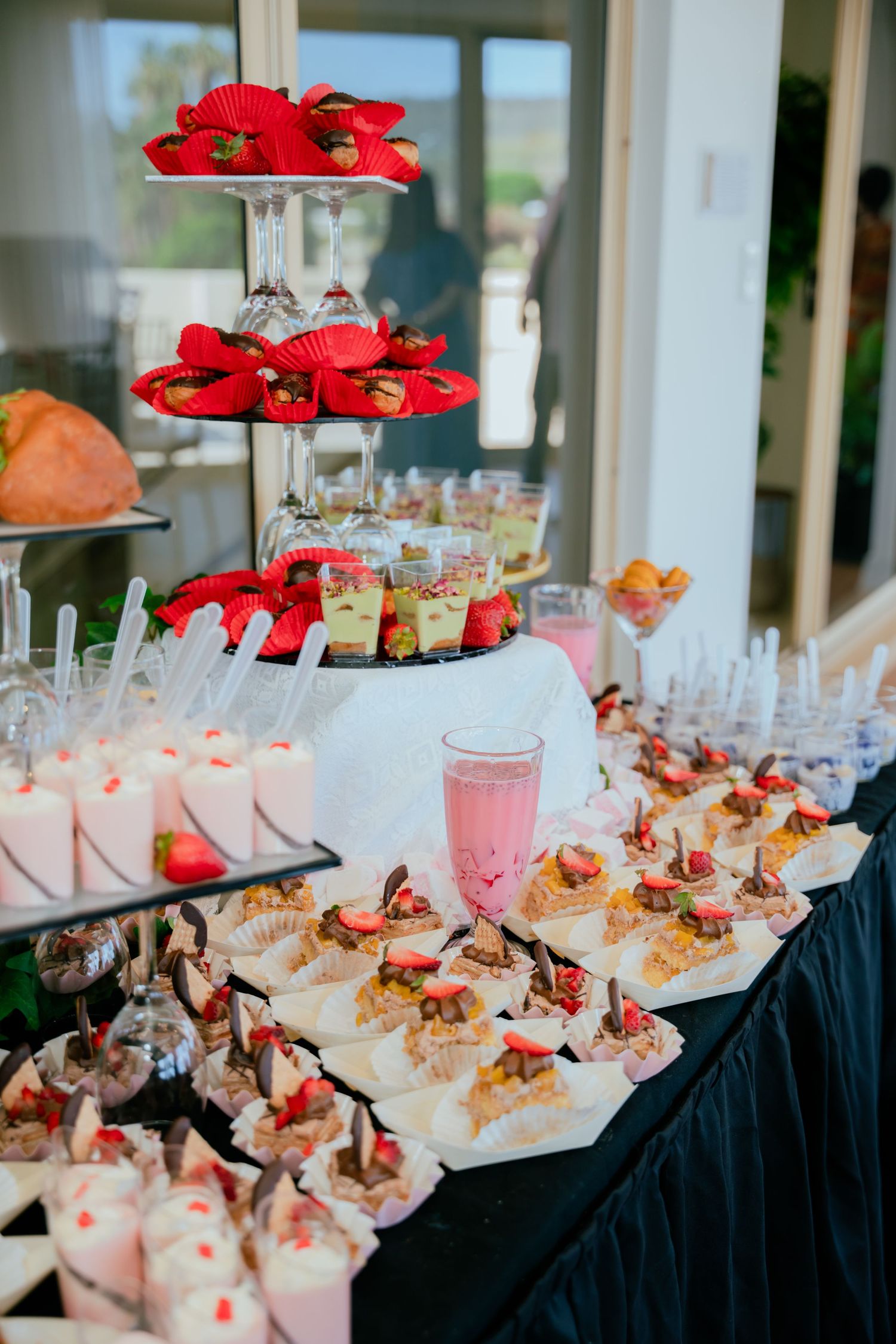 Elaborate dessert table with strawberry treats, mini cakes, and tiered display at birthday party.