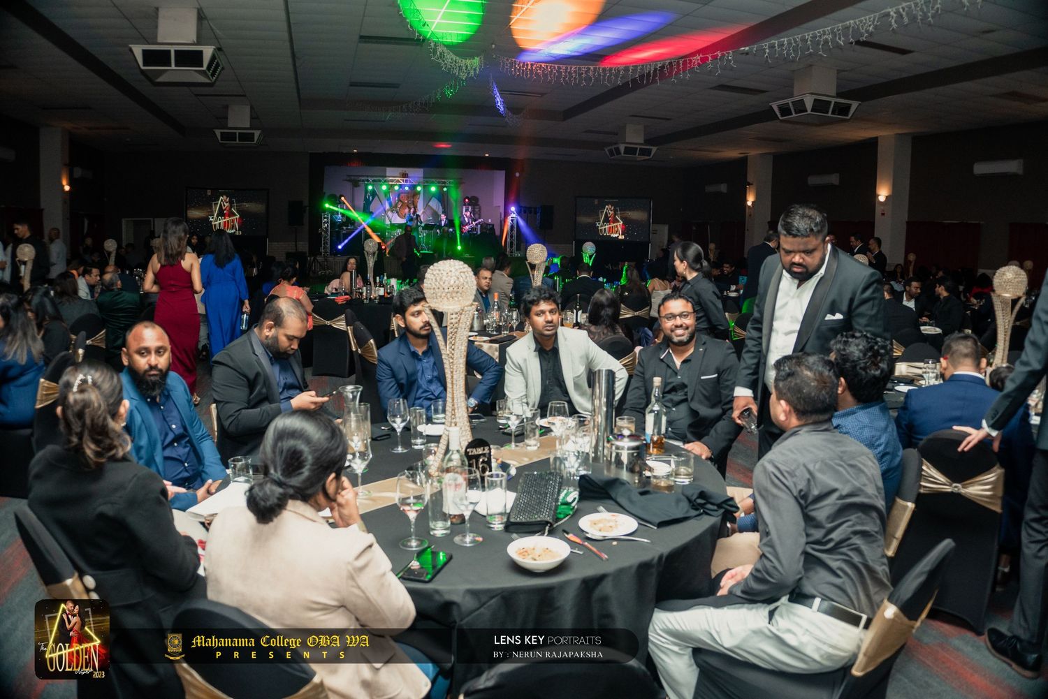 Guests mingling and dining at round tables during a vibrant South Asian gala dinner event.