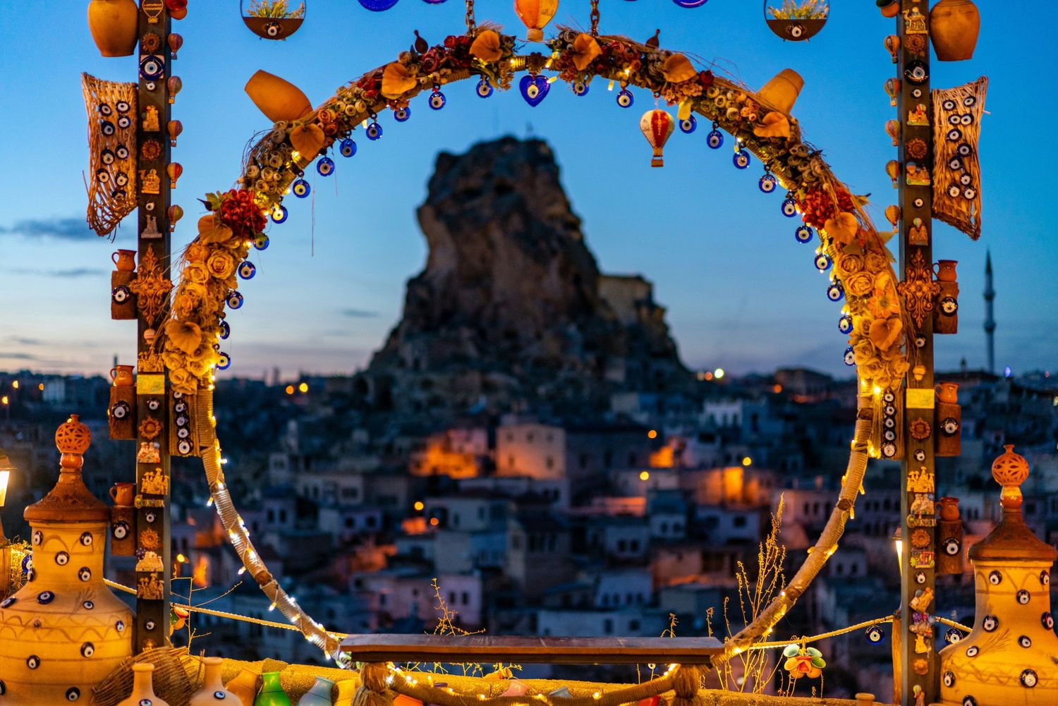 Romantic outdoor terrace decorated with glowing lanterns and string lights overlooking scenic mountain views at dusk.