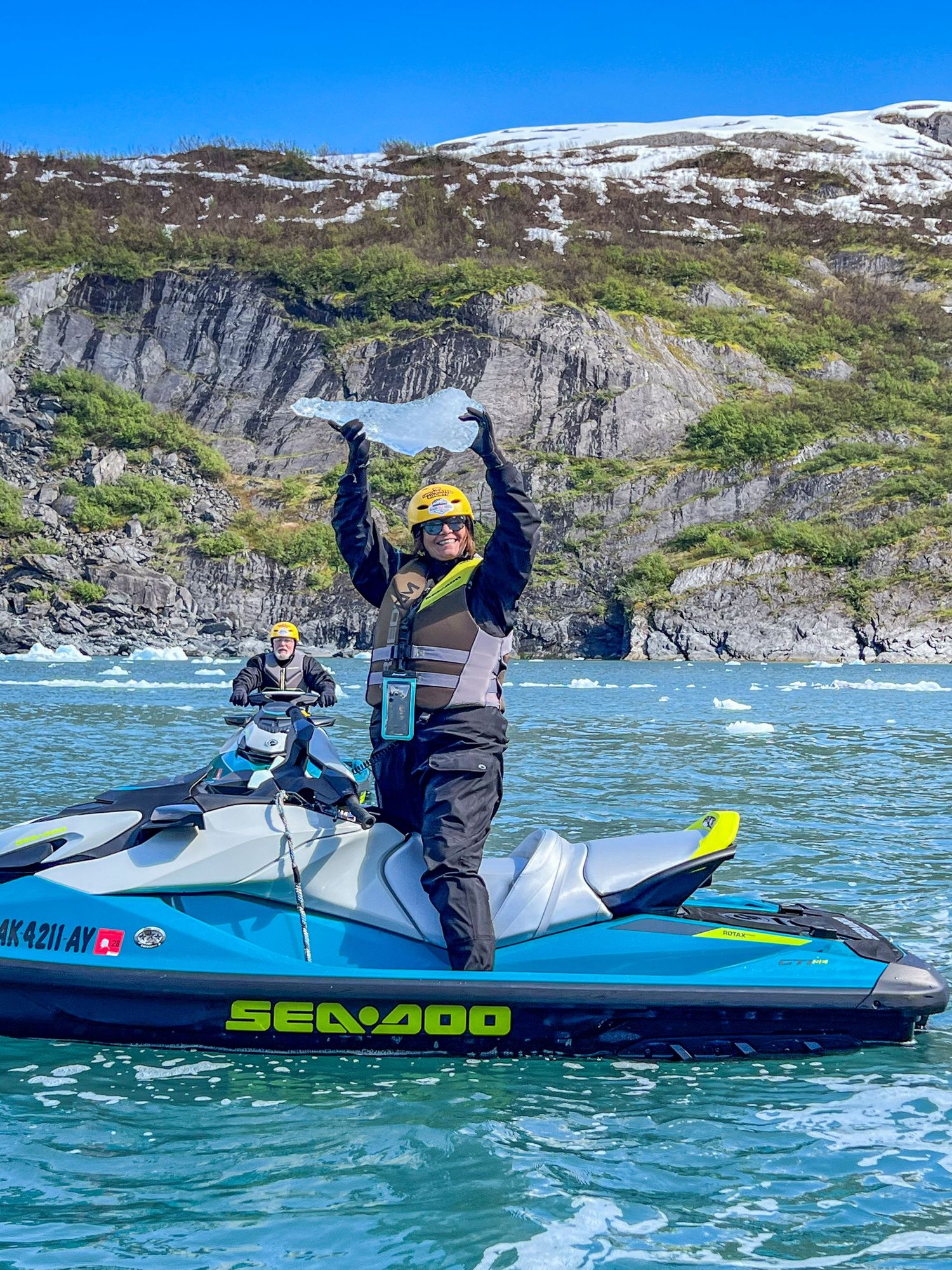Adventure seekers riding Sea-Doo watercraft near dramatic coastal cliffs, Whittier Alaska.