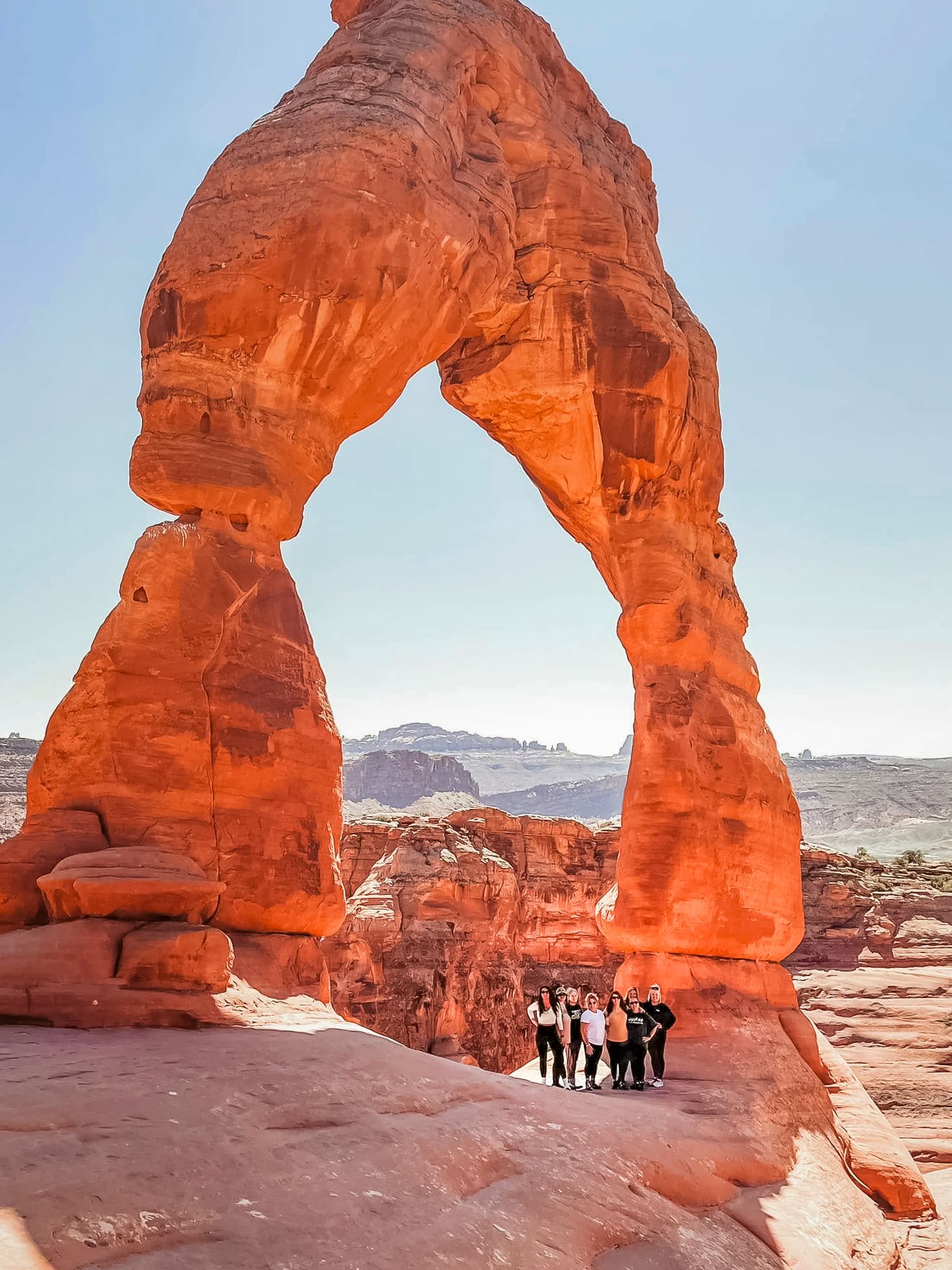 Natural rock arch formations in Arches National Park glowing orange during sunset.