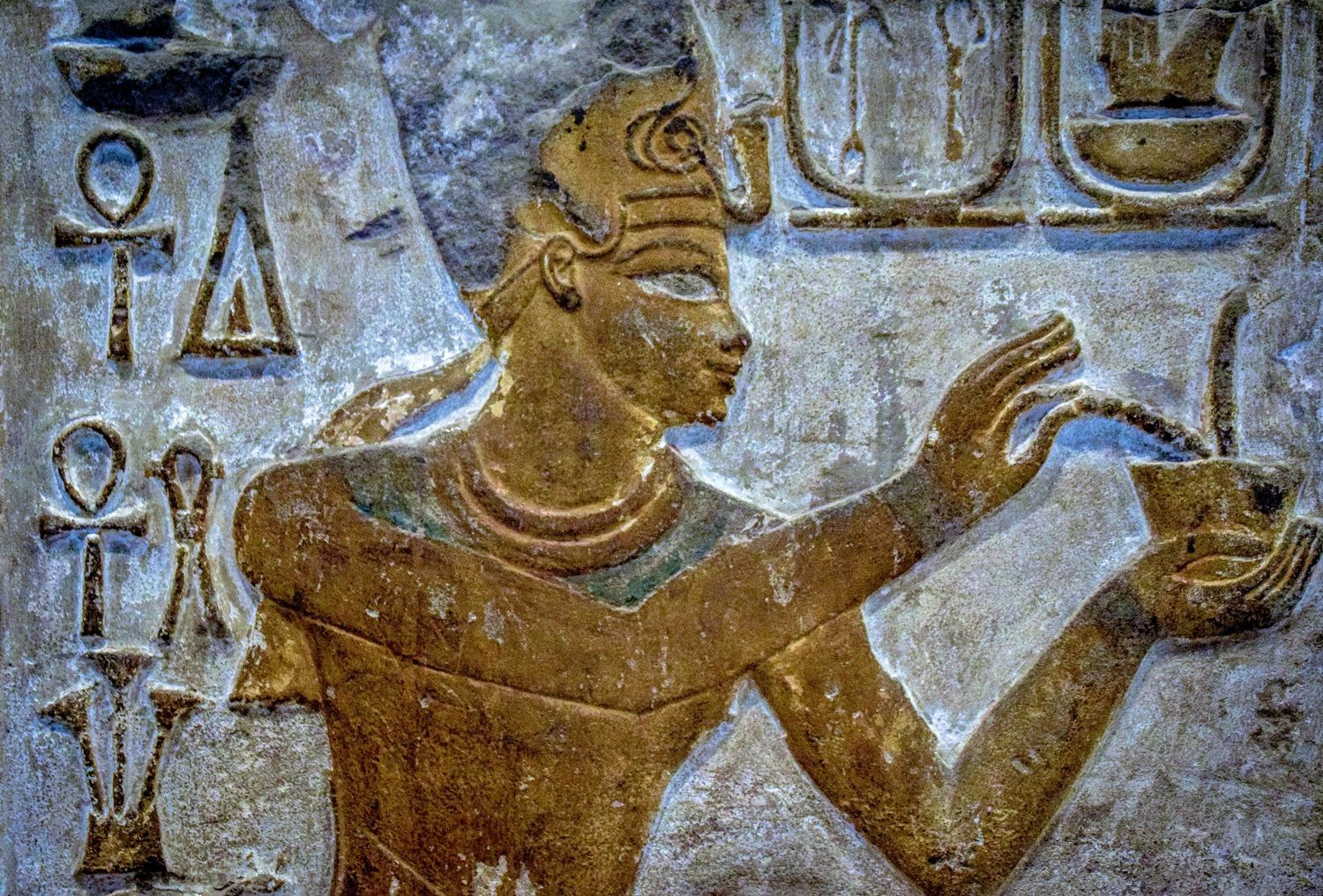 Ancient Egyptian wall relief showing detailed hieroglyphic art in golden tones.