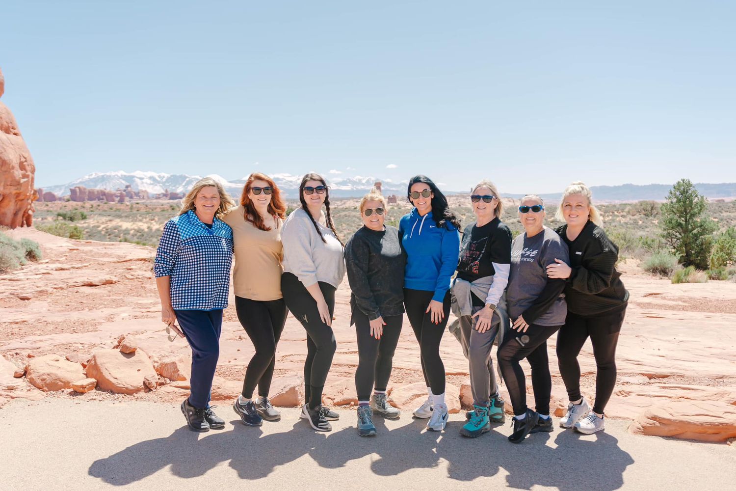 Group of travelers sitting together on red rock formations in an arid desert landscape.