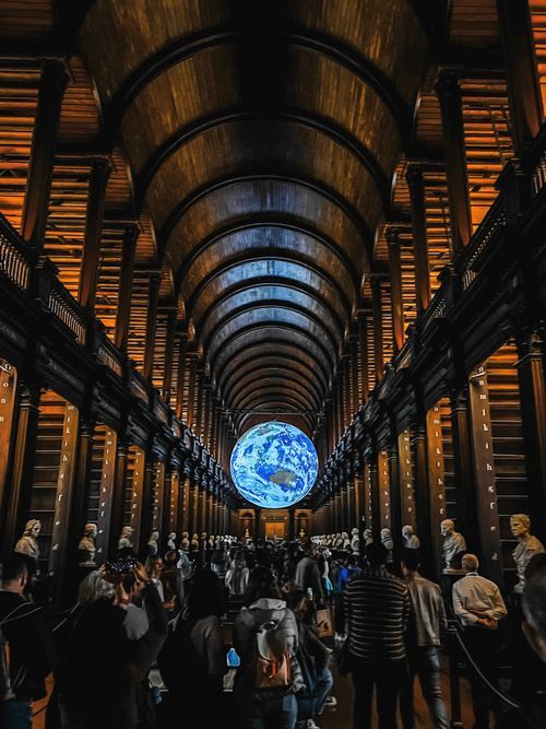 Long Book of Kells exhibition gallery at Trinity College Dublin with illuminated arched ceiling and blue orb display.
