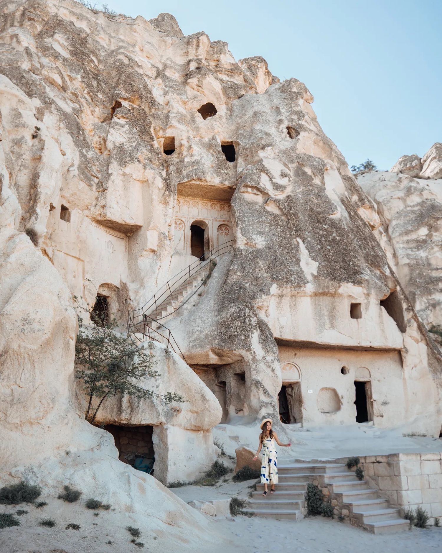Ancient cave churches and dwellings with stone staircases carved into rock face.
