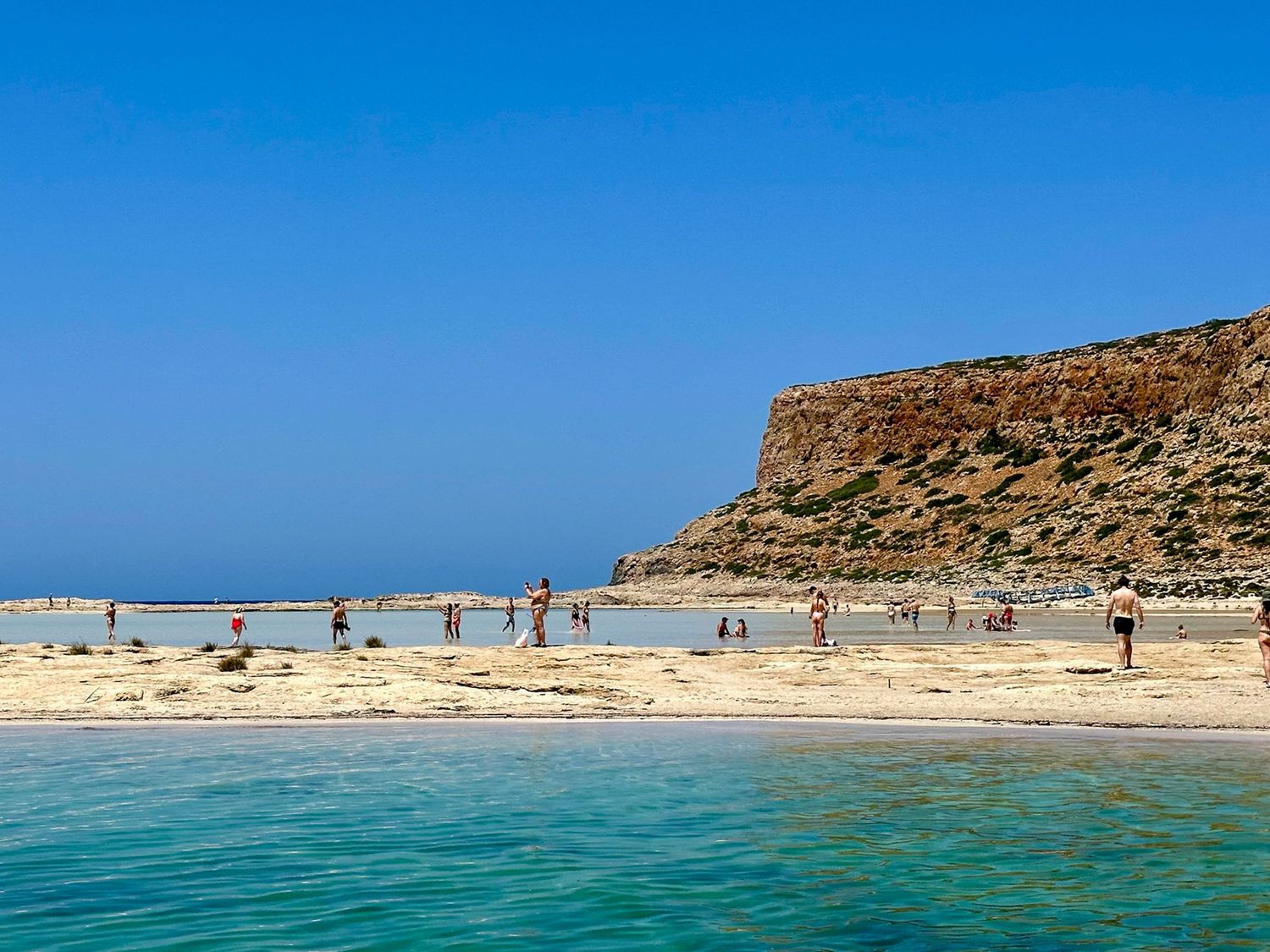 Panoramic view of pristine turquoise waters and white sand beach against clear blue sky.