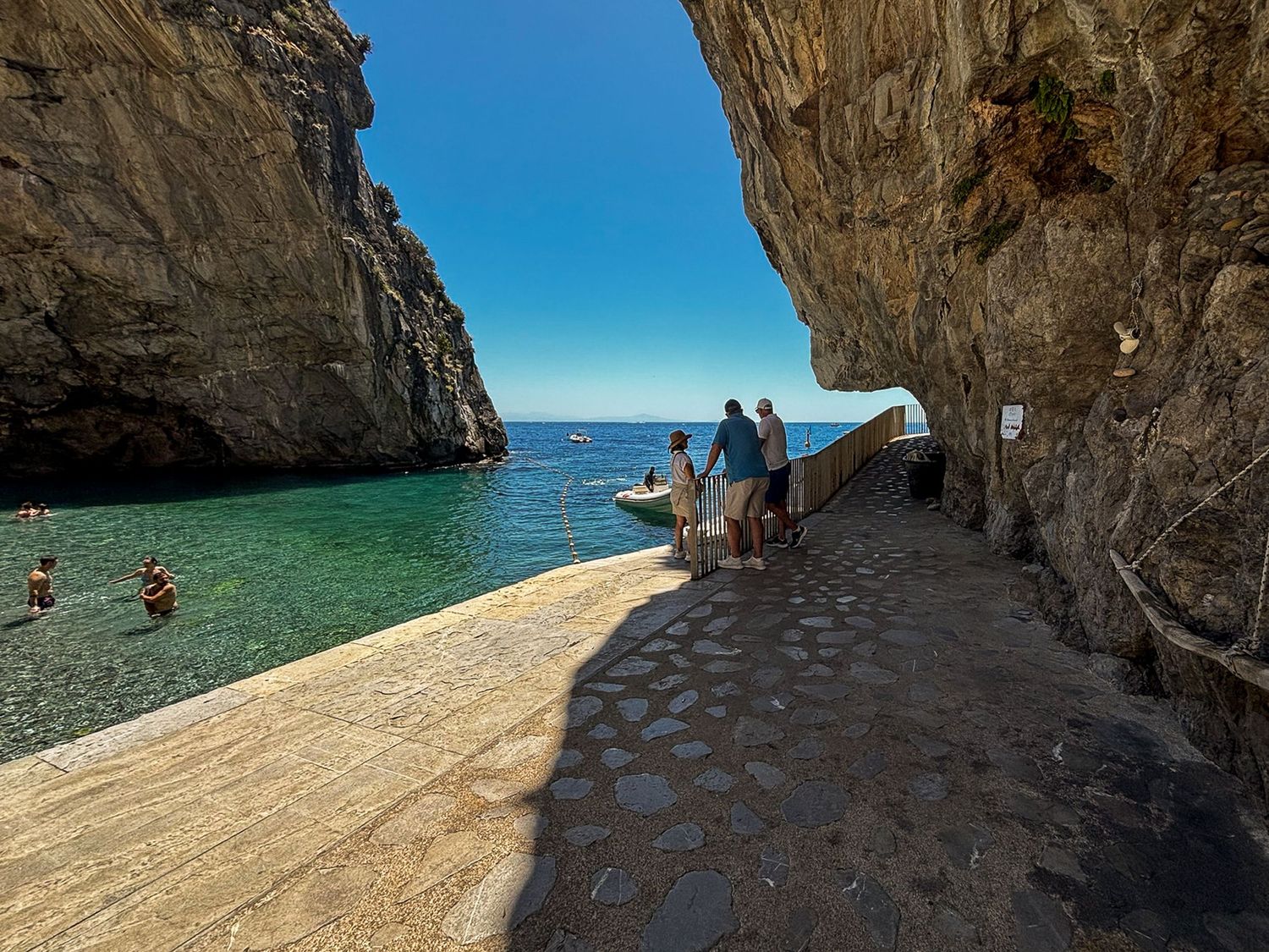 Natural stone archway over a crystal clear Mediterranean beach cove.