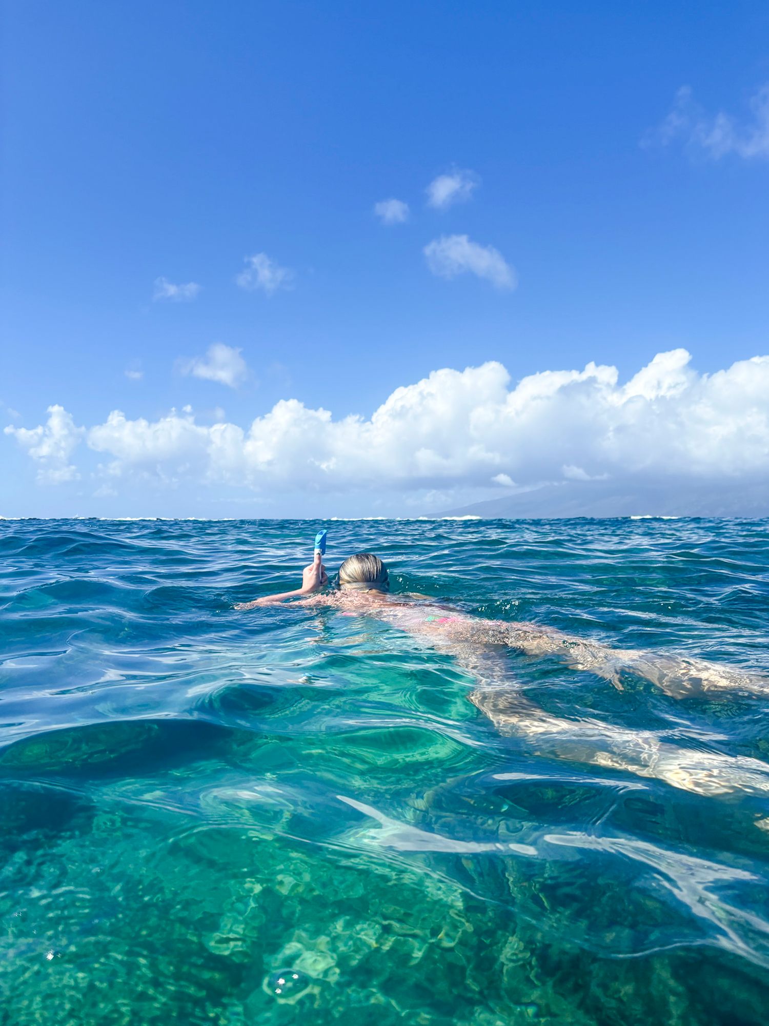 Crystal clear turquoise waters with snorkeling activity visible from split-level underwater perspective.