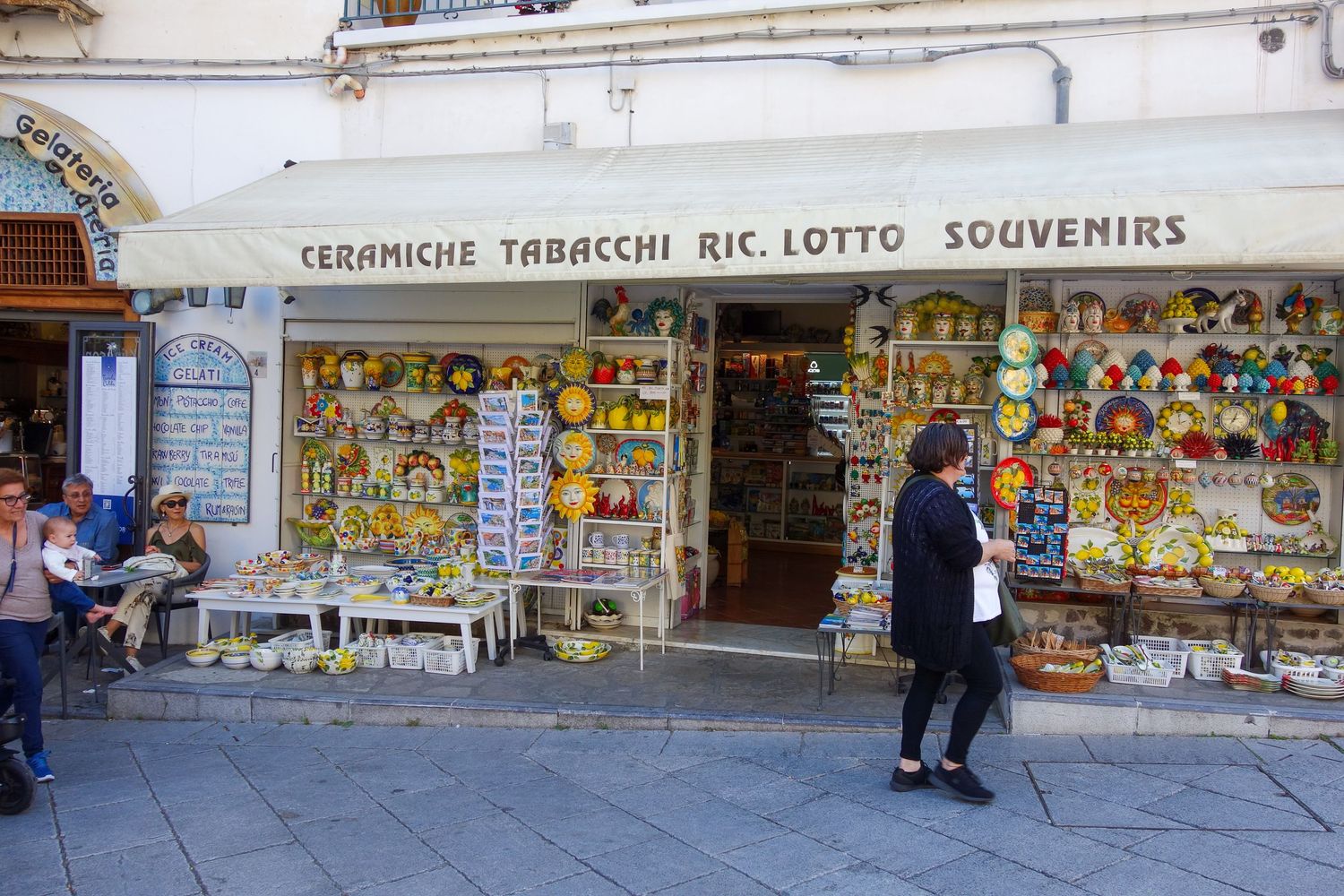 Row of vibrant street vendors selling souvenirs and local goods along a Mediterranean walkway.