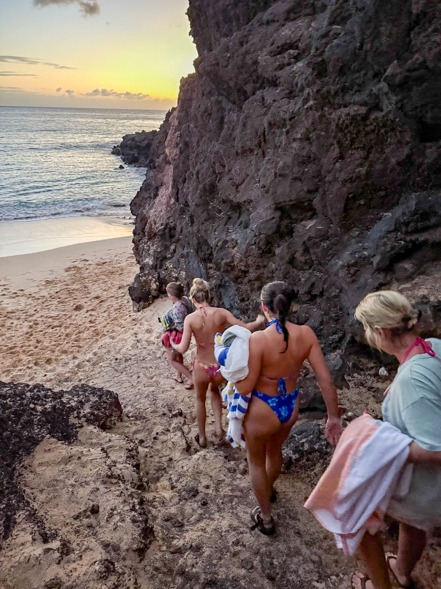 Scenic rocky beach cove at sunset with ocean waves in background.