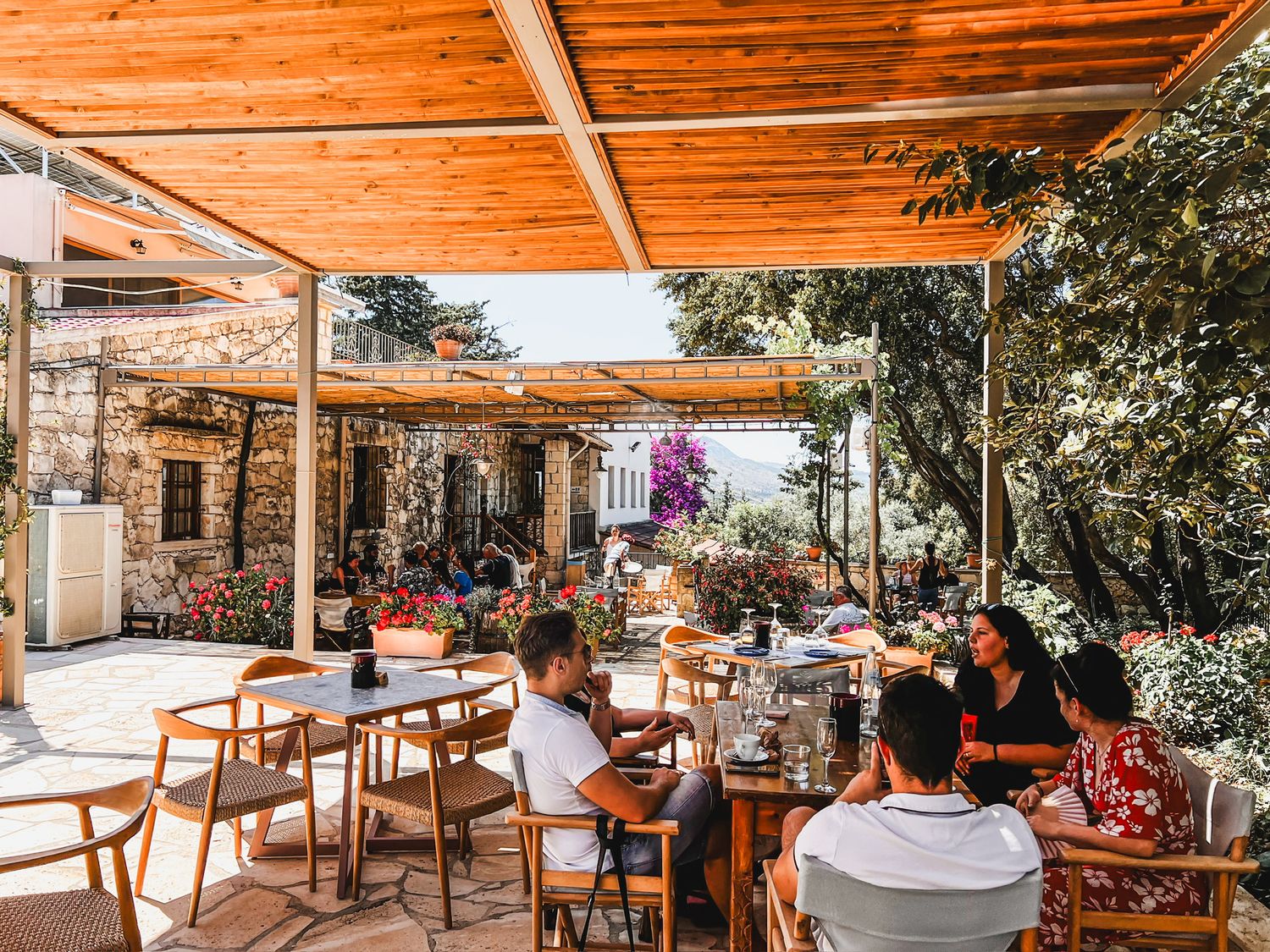 Restaurant terrace with wooden pergola and seating areas offers a cozy outdoor dining space in natural lighting.