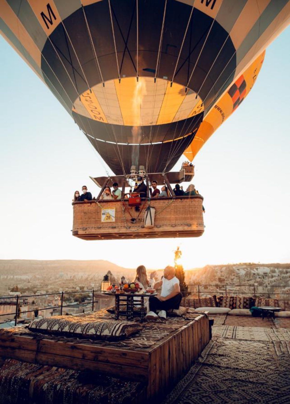 Hot air balloon basket with passengers viewing scenic landscape from above.