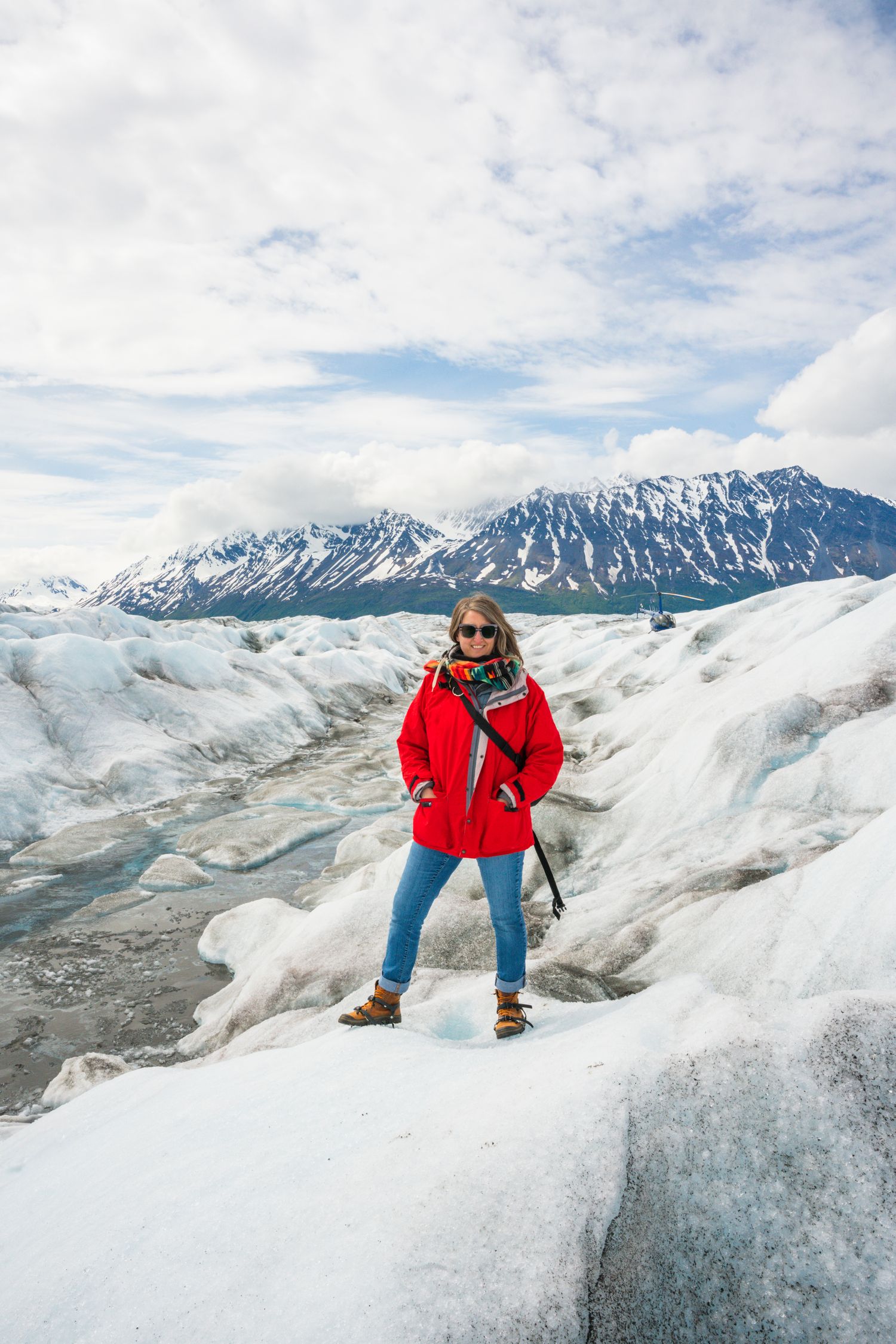 Adventure seeker standing on Knick Glacier with snowy mountains in background.