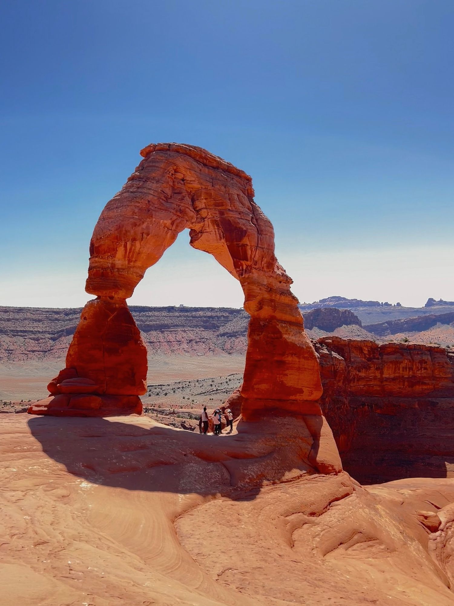 Delicate Arch, a natural sandstone formation in Arches National Park, Utah, photographed from different angles against blue sky.