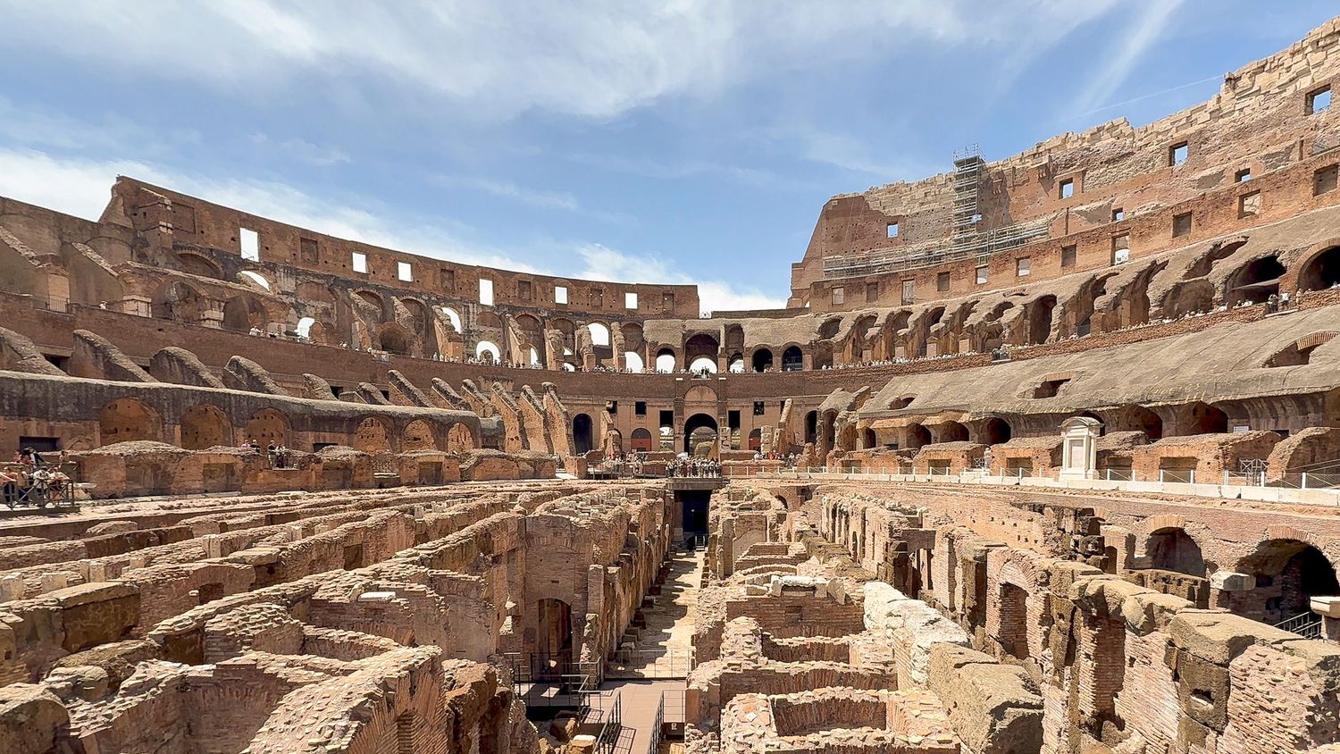 Panoramic interior view of the Colosseum's tiered seating and archways in Rome.