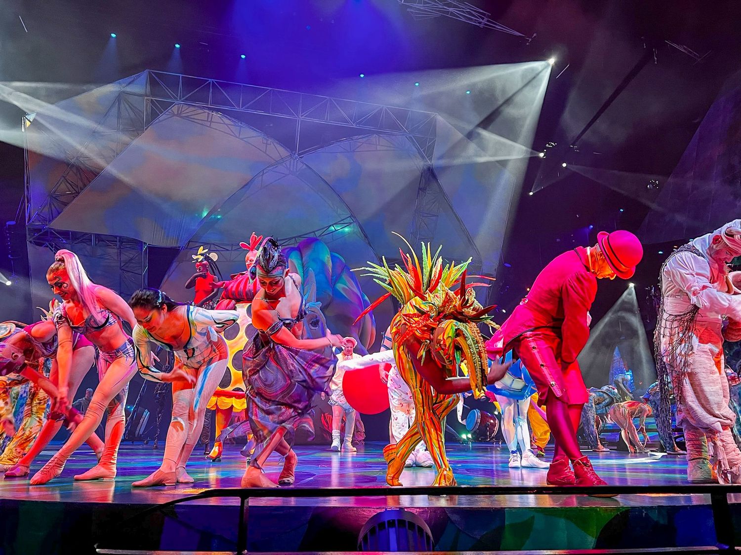 Performers in colorful costumes dancing on stage during a theatrical show.