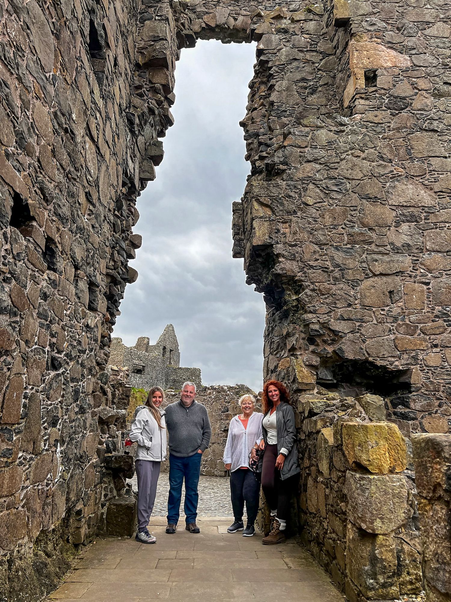 Ancient stone castle walls and archways with visitors exploring the medieval architecture.