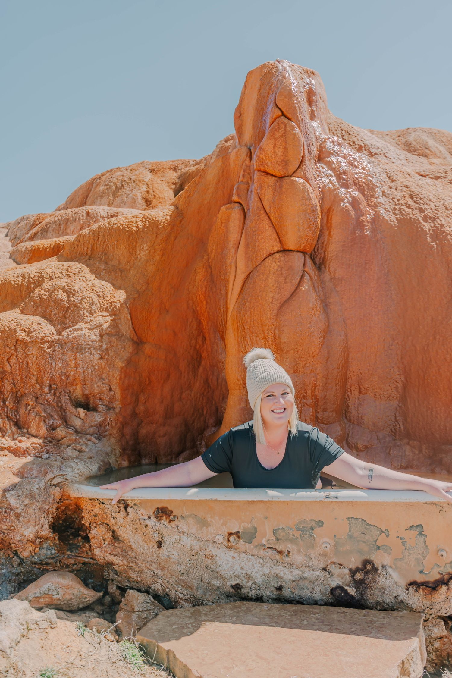 People posing playfully in a natural rock hot springs in Utah.