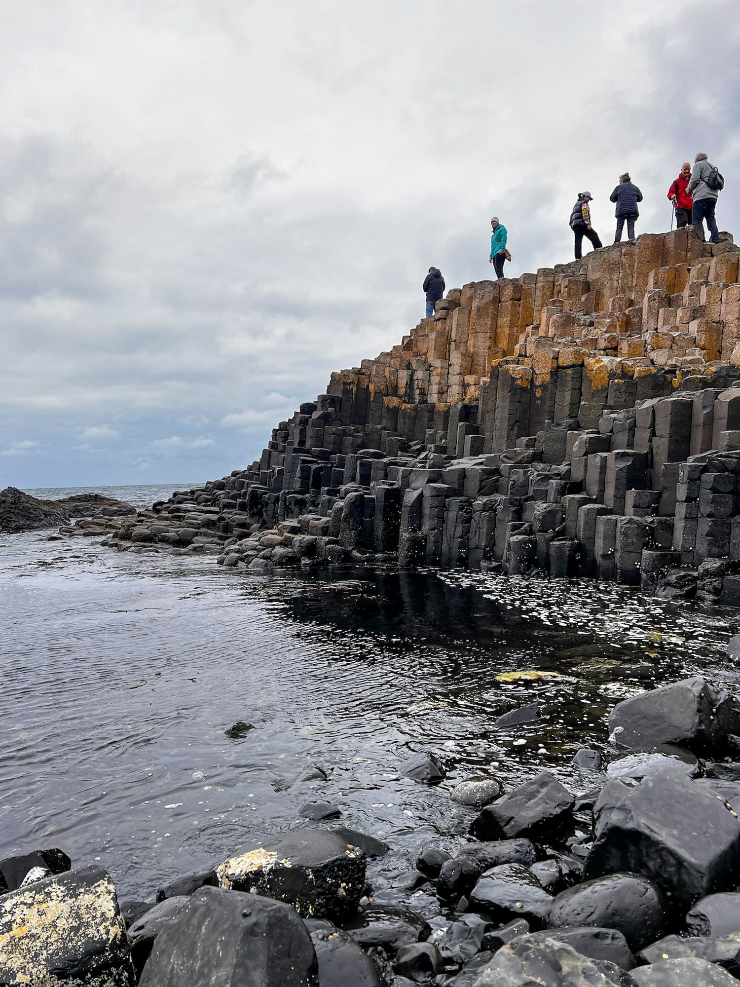Dramatic basalt columns and rock formations at Giant's Causeway in Northern Ireland under cloudy skies.