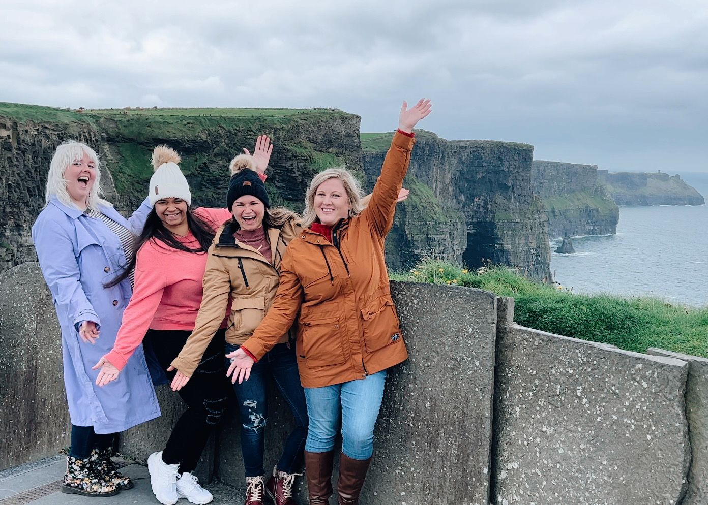 Group of tourists enjoying views from the scenic Cliffs of Moher in Ireland on a cloudy day.