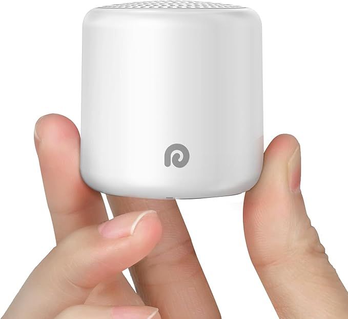 Small white cylindrical portable speaker held between fingers showing compact size and minimalist design.
