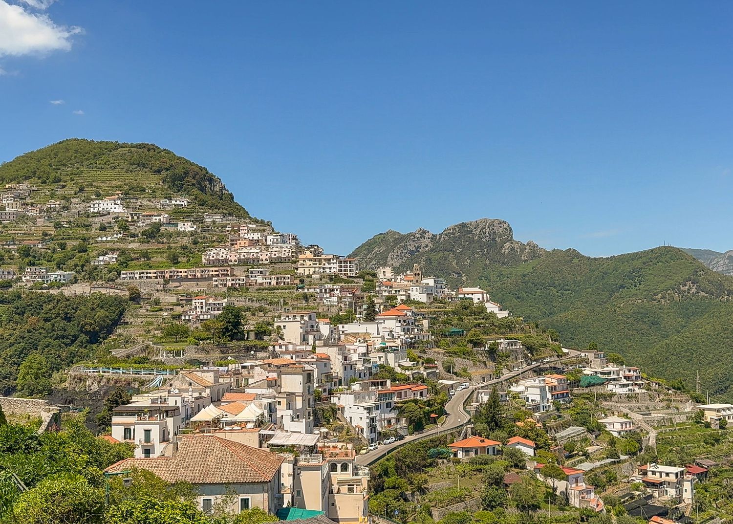 Panoramic view of hillside houses and buildings cascading down the Amalfi Coast.