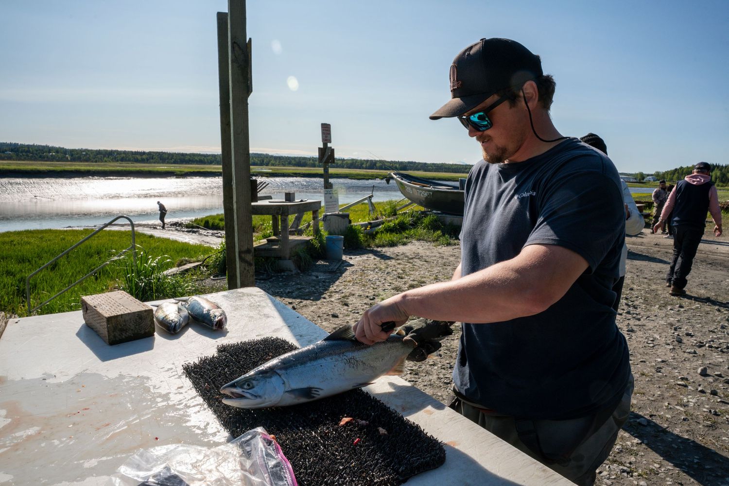 Outdoor preparation station with fishing equipment and supplies near waterfront.