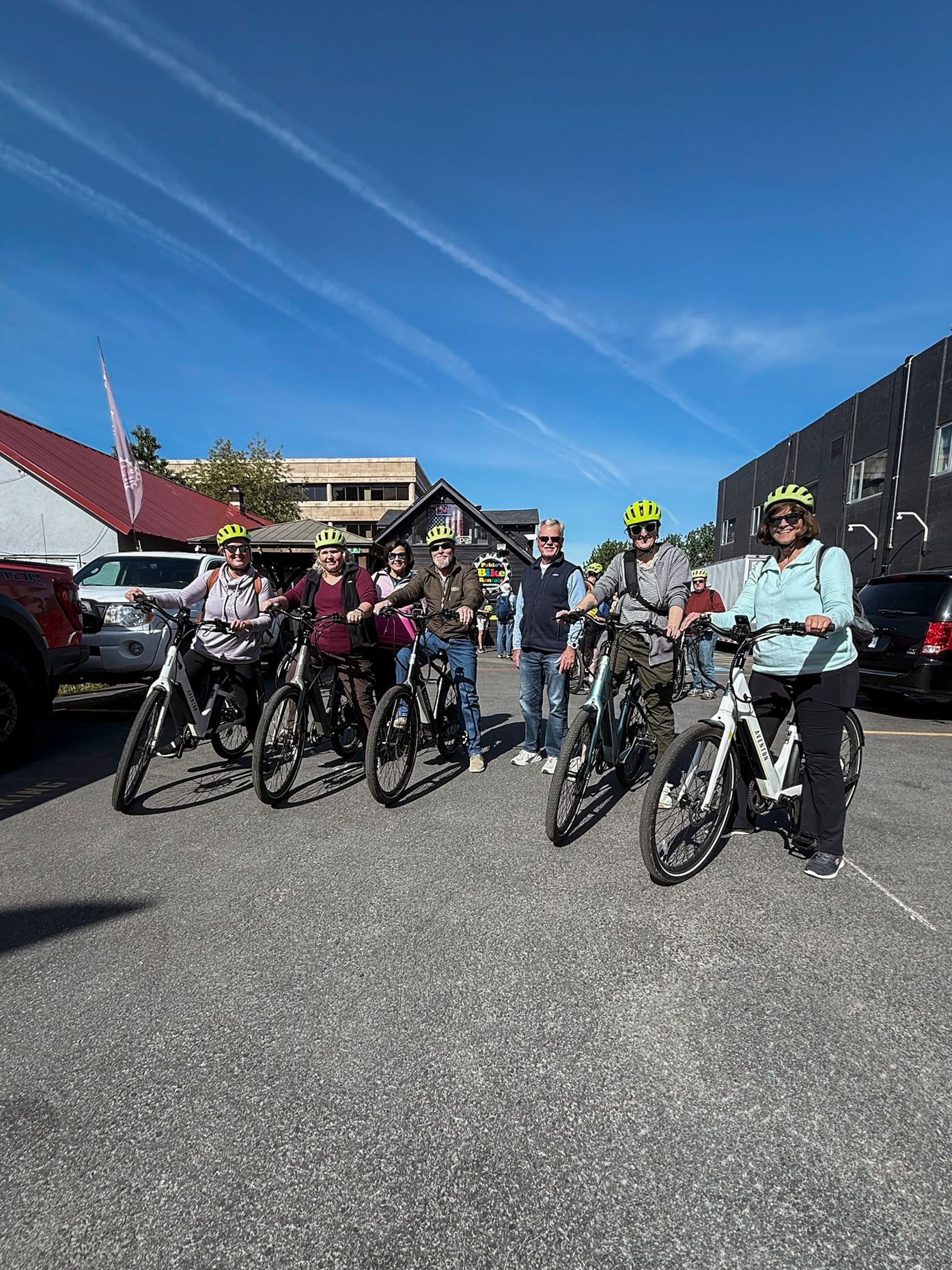 Line of parked bicycles on asphalt with buildings in background on sunny day.