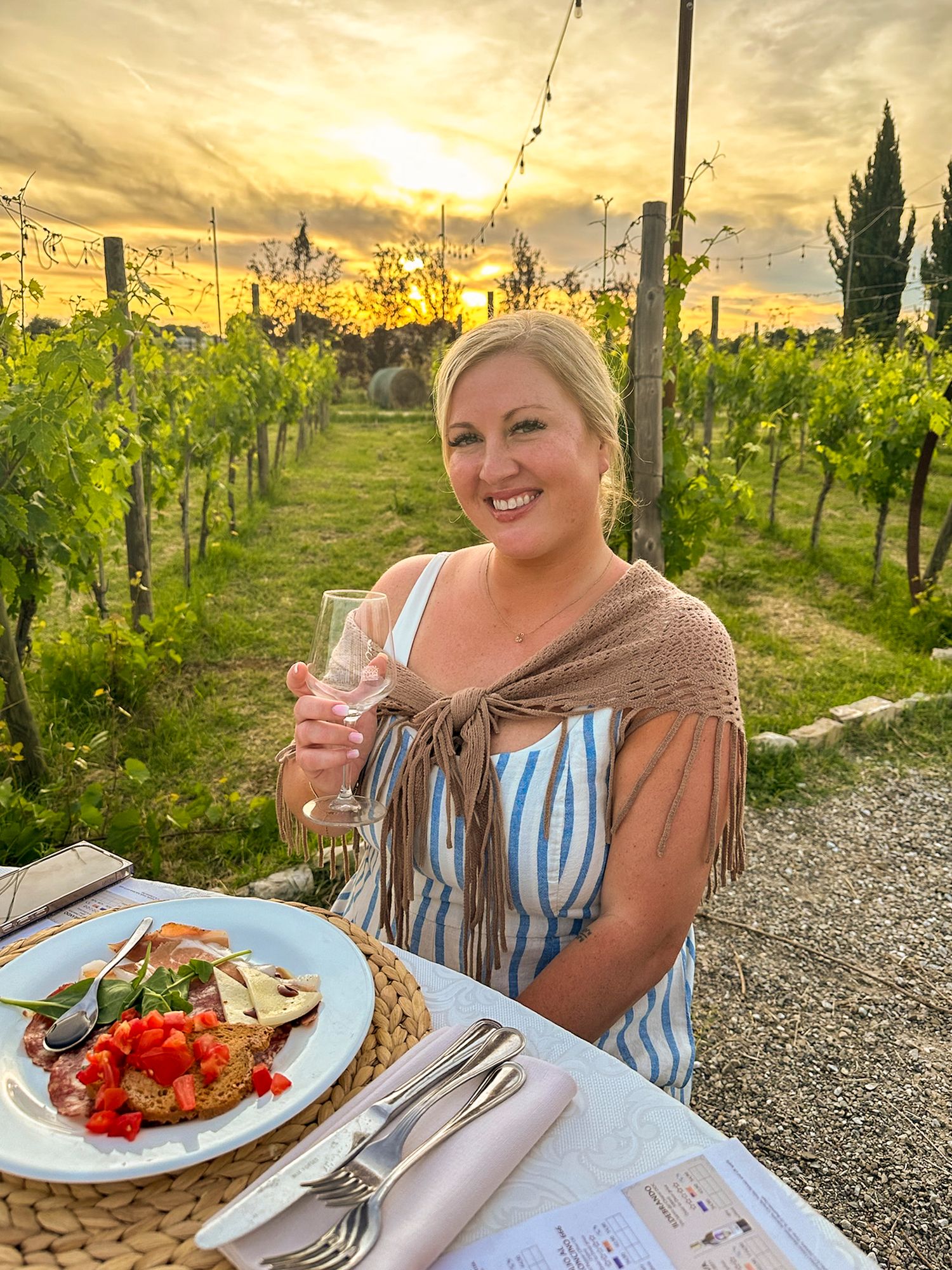 Outdoor vineyard dining experience at sunset with fresh food and wine among the grapevines.