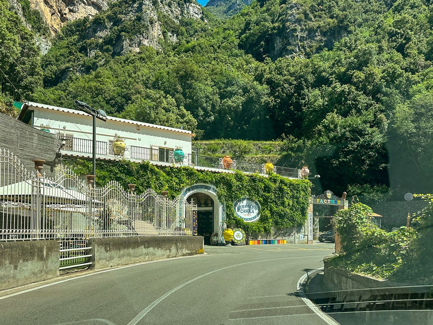 Winding coastal road with stone walls and lush greenery along the Amalfi Coast.