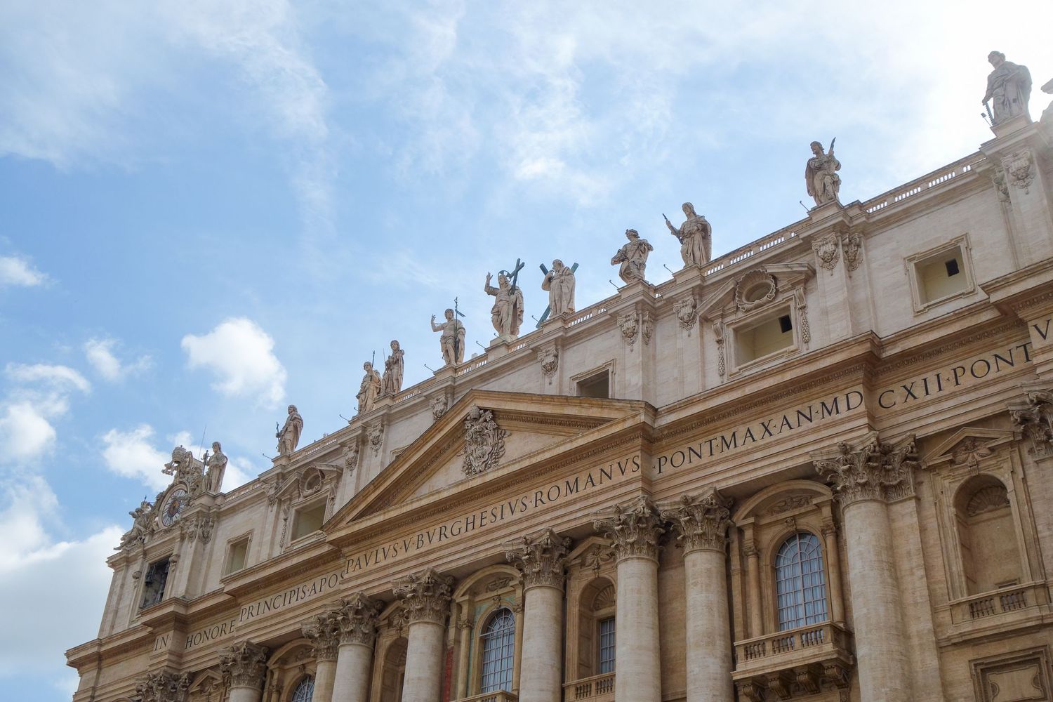 Ornate architectural details of St. Peter's Basilica facade with classical statues and columns in Vatican City.