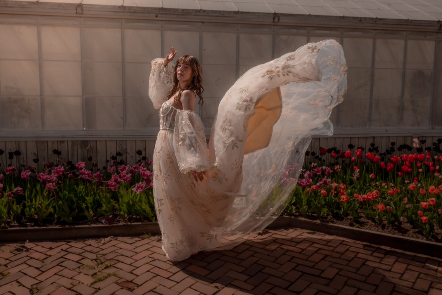 A sequence of motion shots showing a plastic bag floating and dancing through the air against a building wall and flower bed.