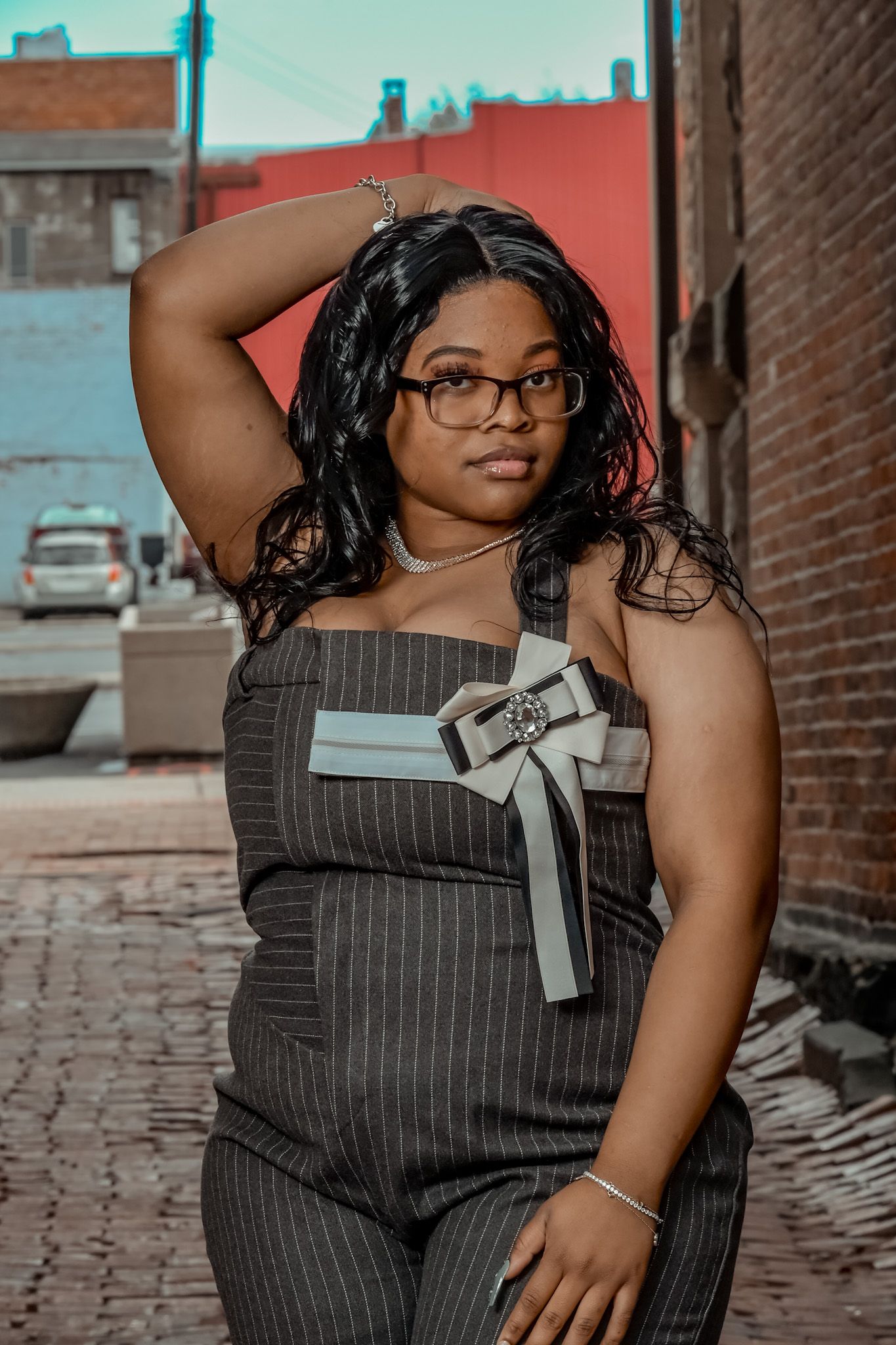 Professional portrait session featuring a pinstripe jumpsuit against an urban brick backdrop.