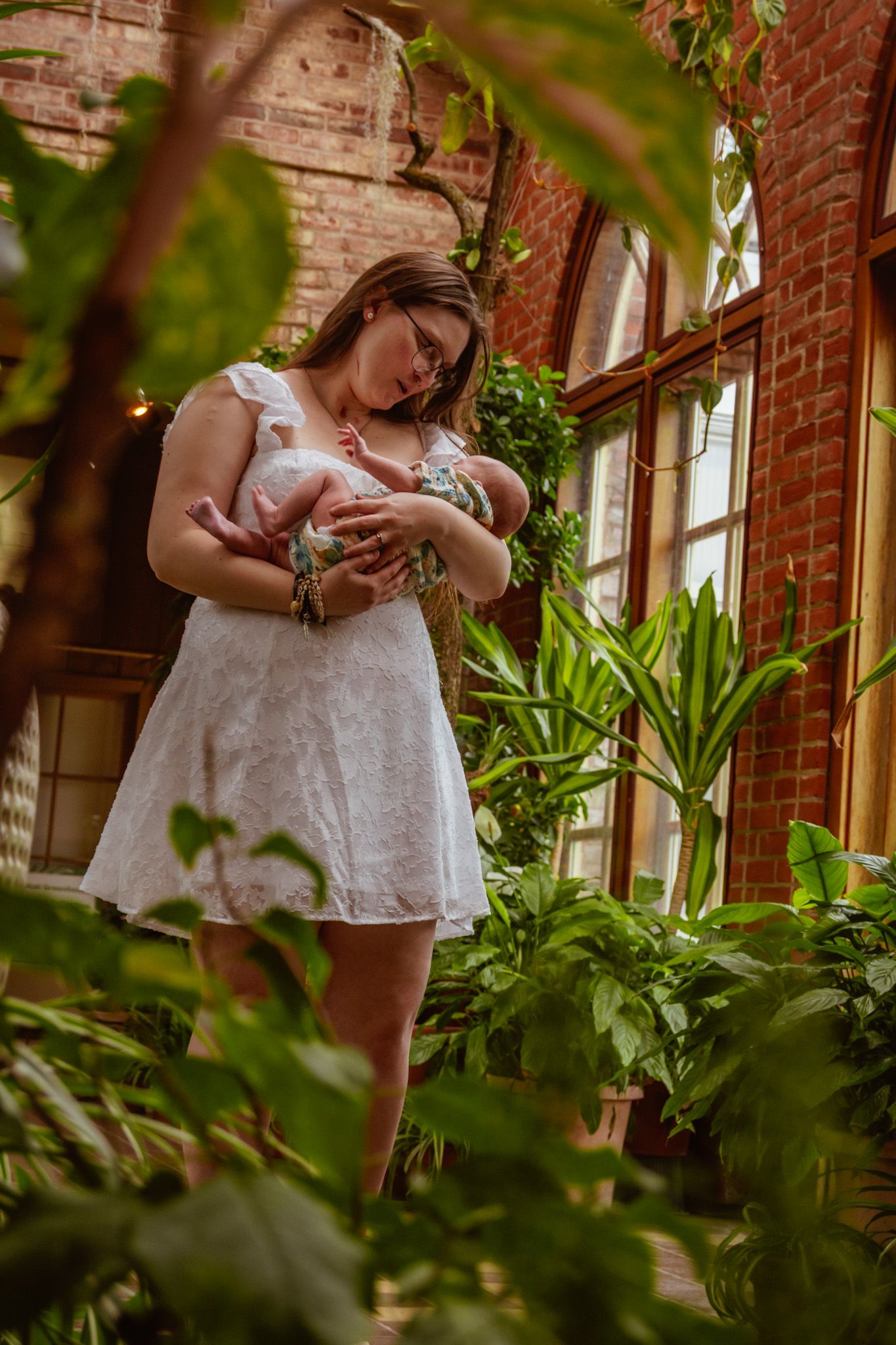 A serene indoor garden scene with white dress against exposed brick wall and lush green plants.