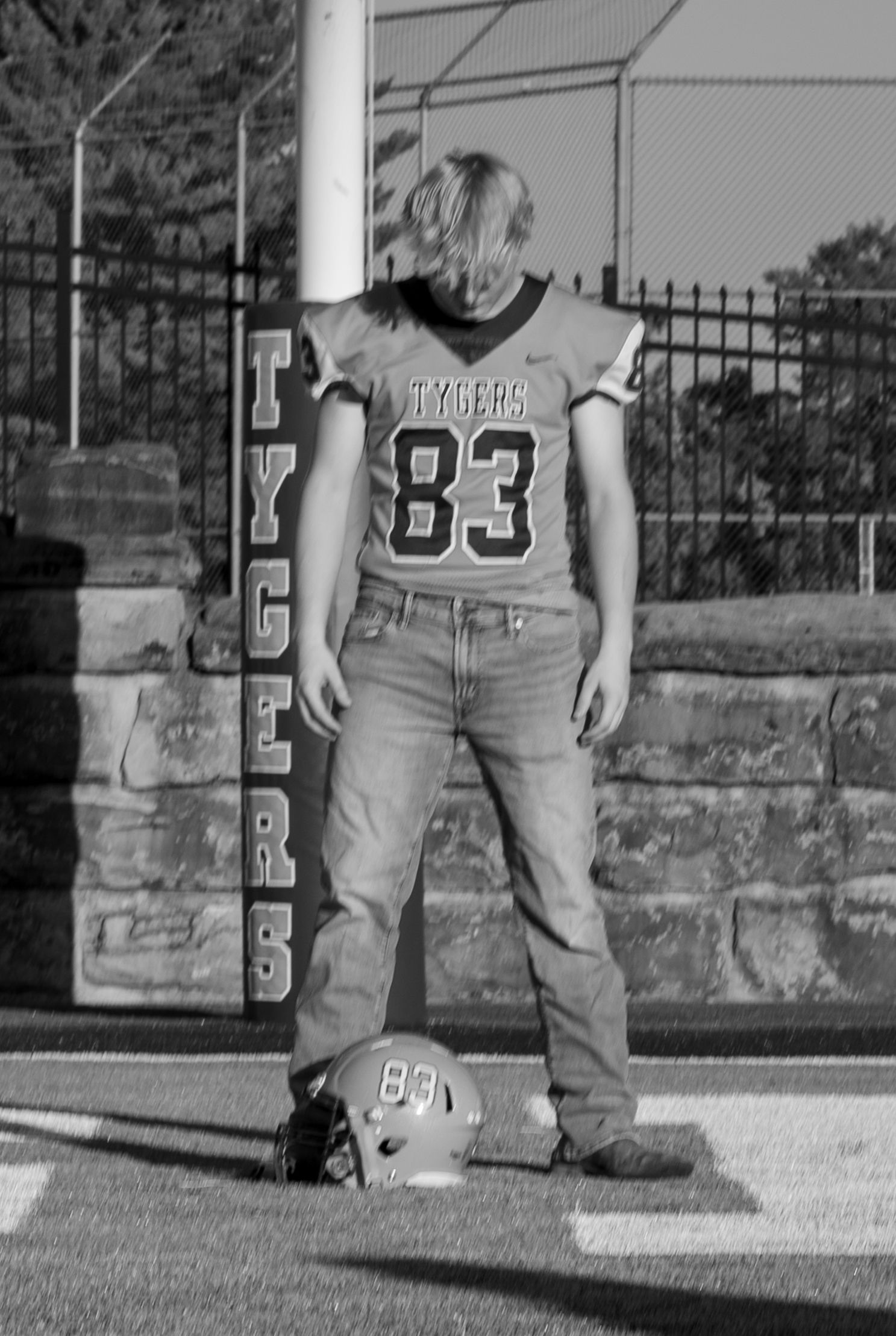 Black and white photo of a young football player wearing jersey number 83 for the Tygers team, standing on a field.