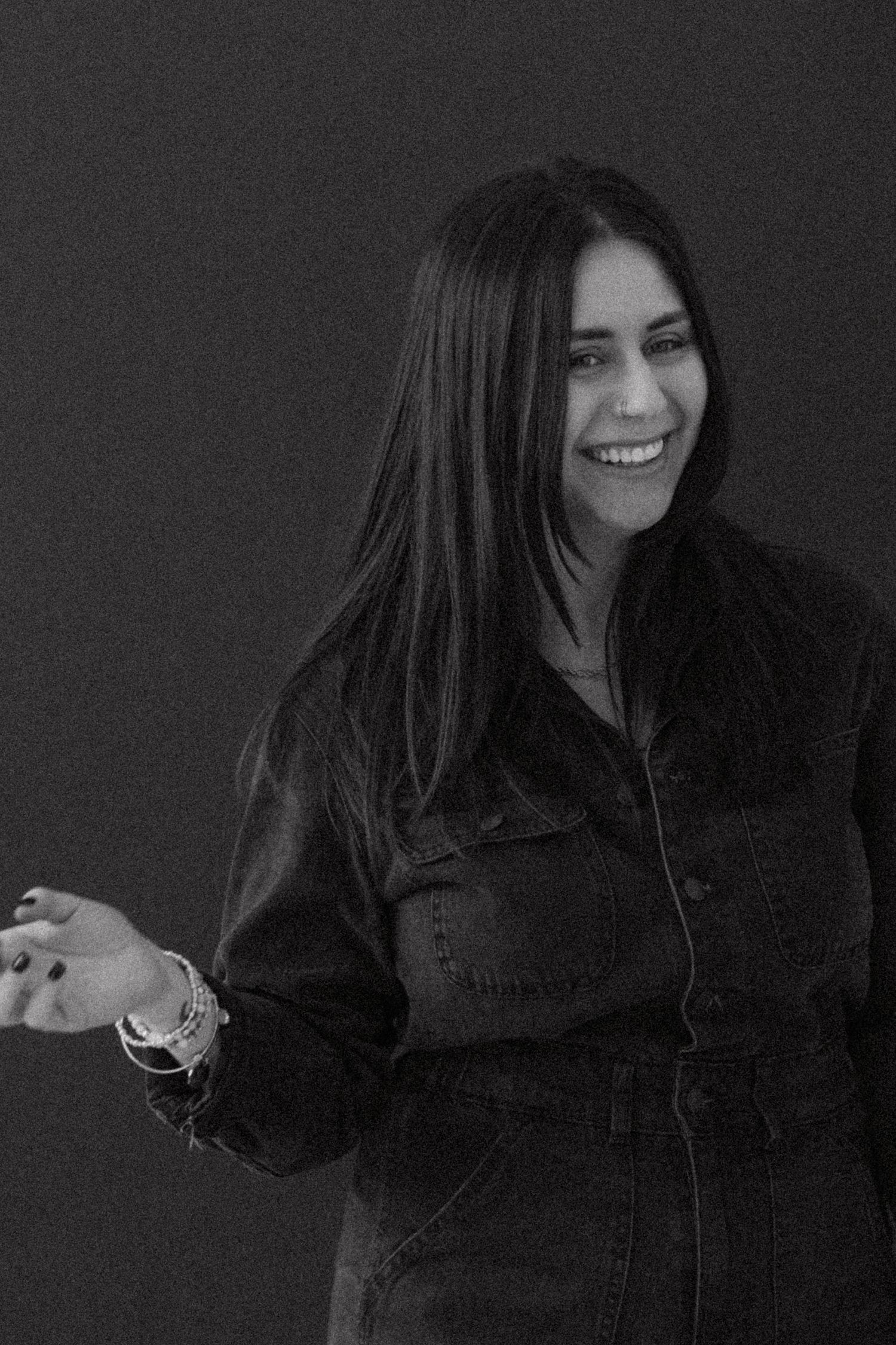 Person in dark clothing makes animated gestures during studio photoshoot.