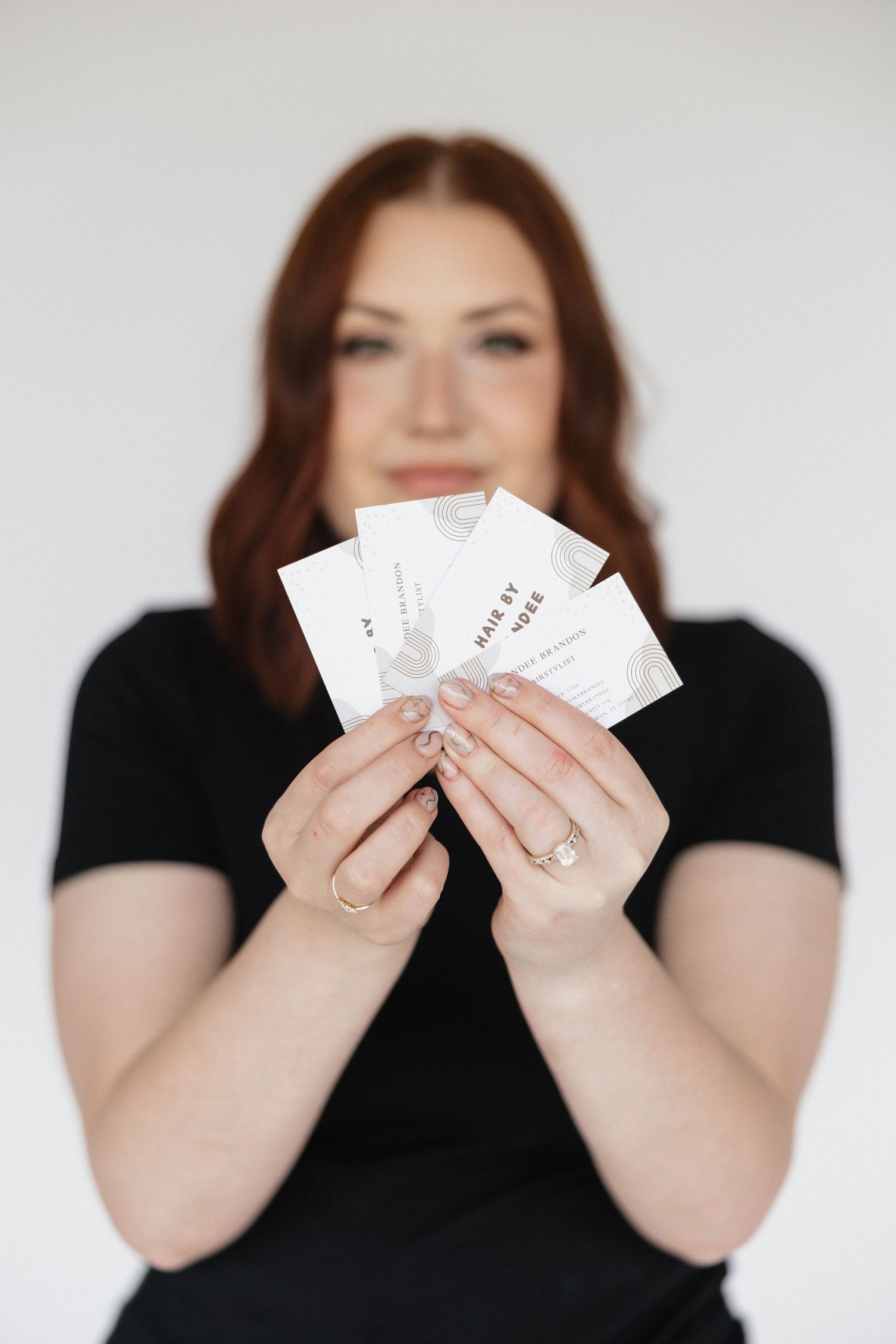 Person in black shirt displaying hair extension brand cards.