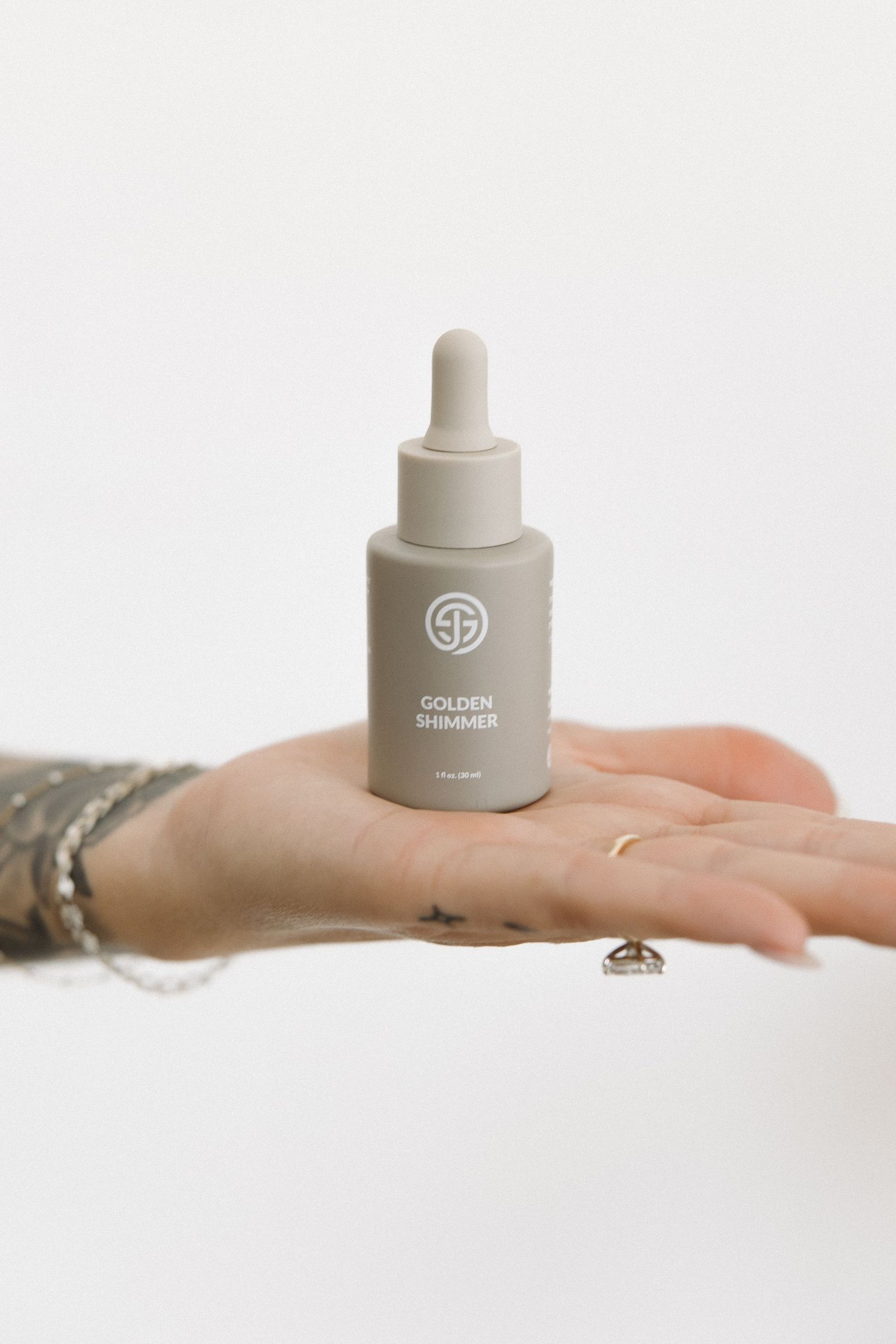 Close-up of a hand holding a small SJOLIE dropper bottle with Golden Thunder product label.