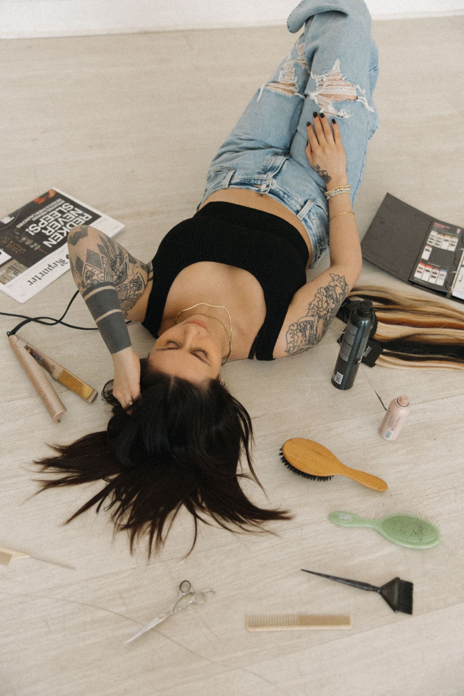 Beauty and hair styling tools scattered on light wooden floor.