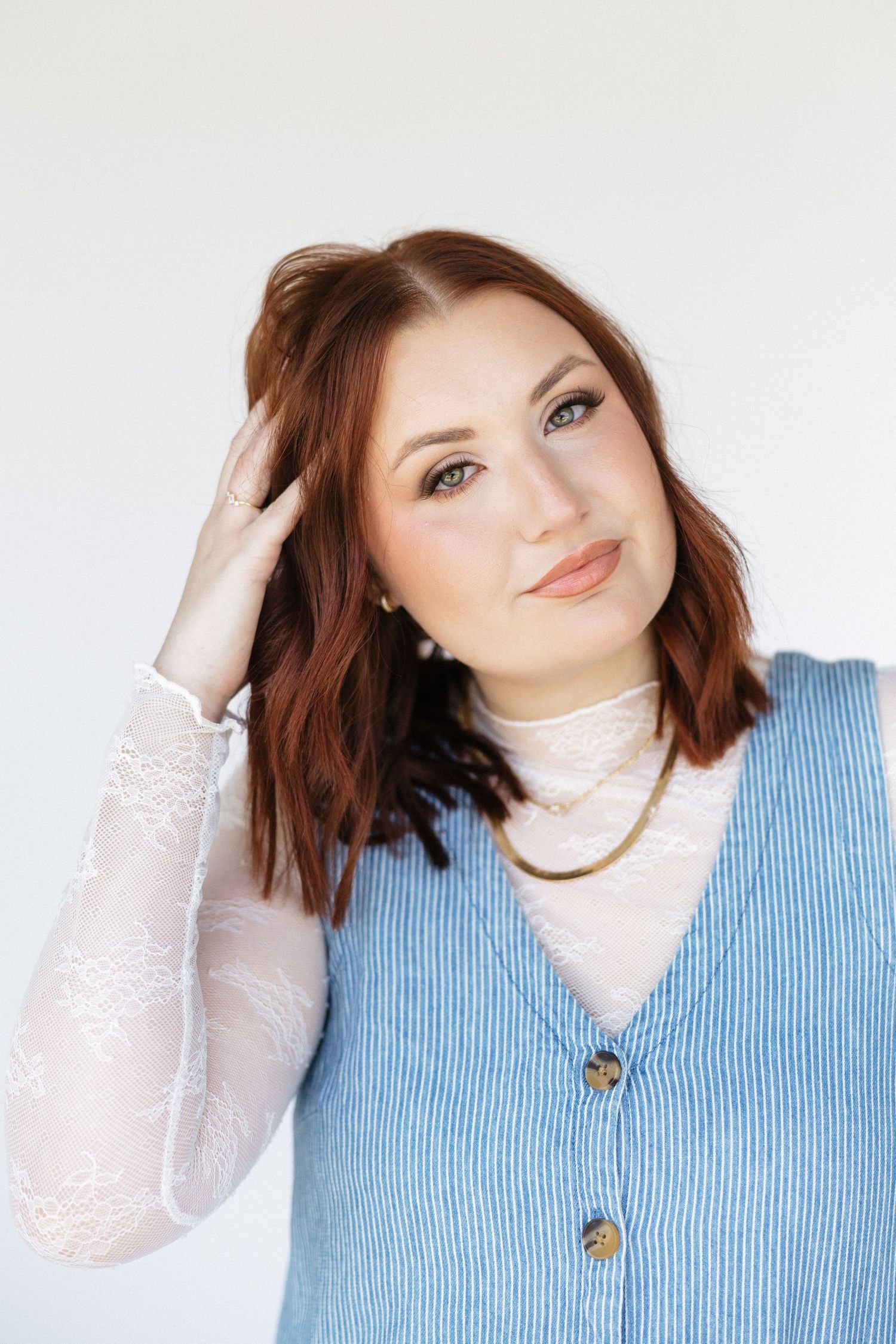 Someone wearing a light blue corduroy vest with white lace sleeves poses against a white background.