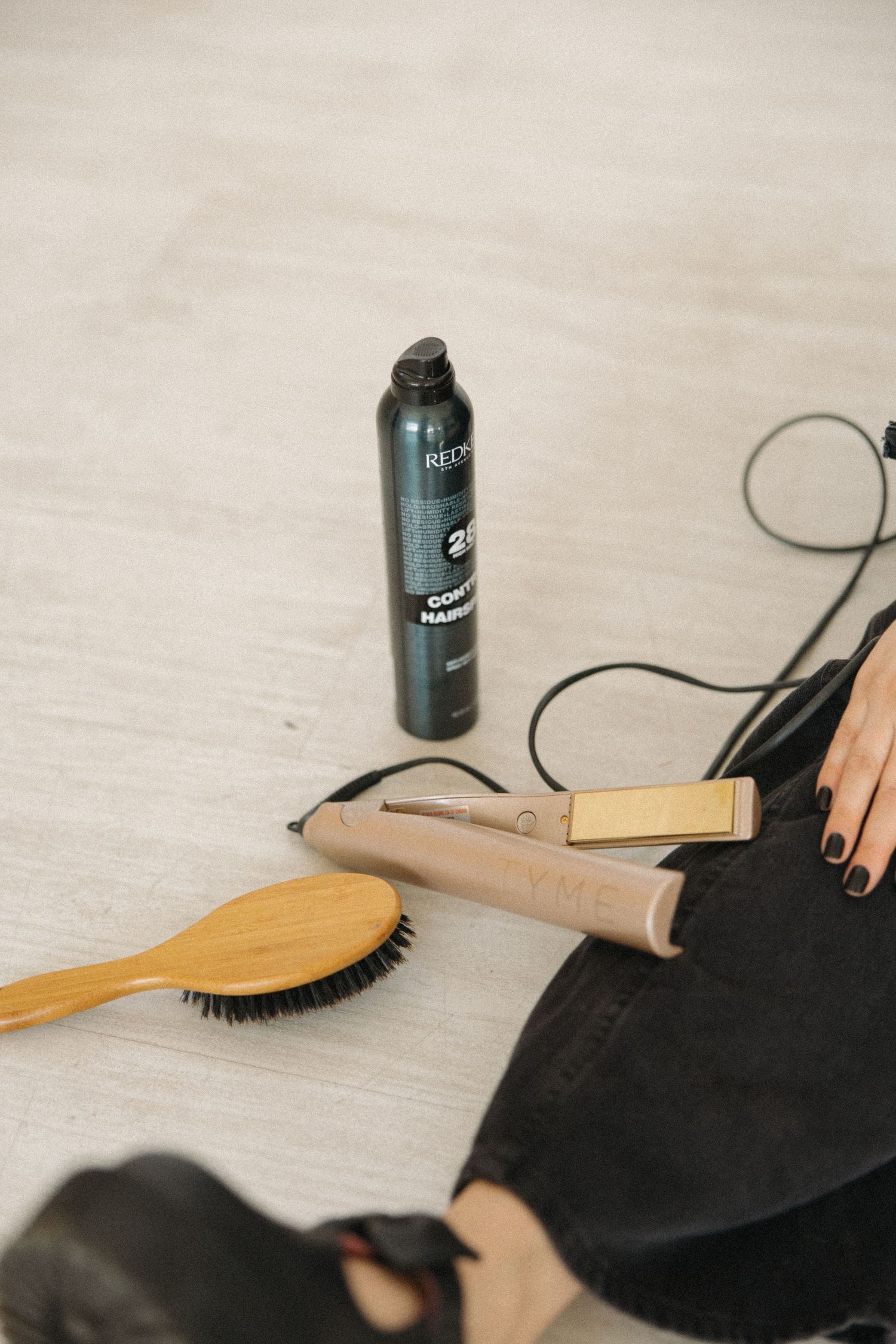 Wooden hairbrushes and styling products arranged on light wooden surface.