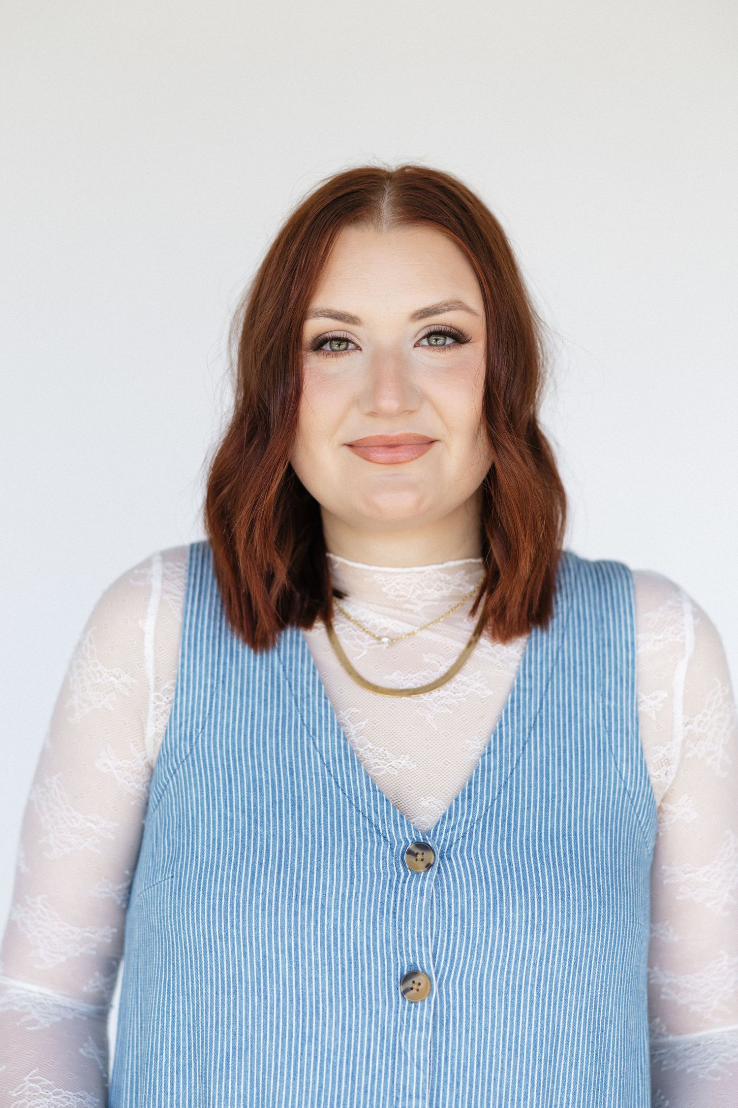 Portrait in blue striped vest and white lace blouse against white background.