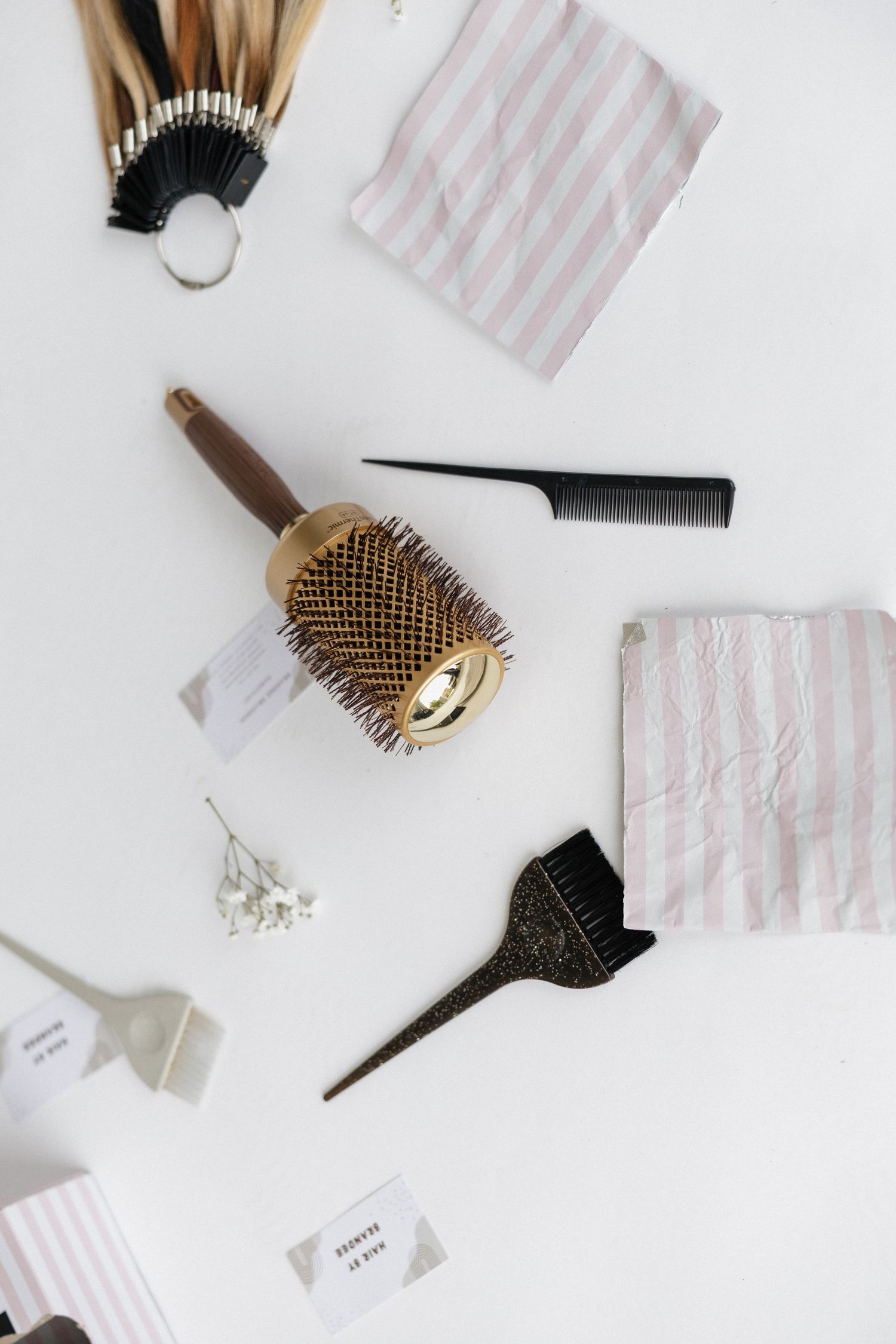 Collection of hair styling brushes and beauty tools arranged on white surface.
