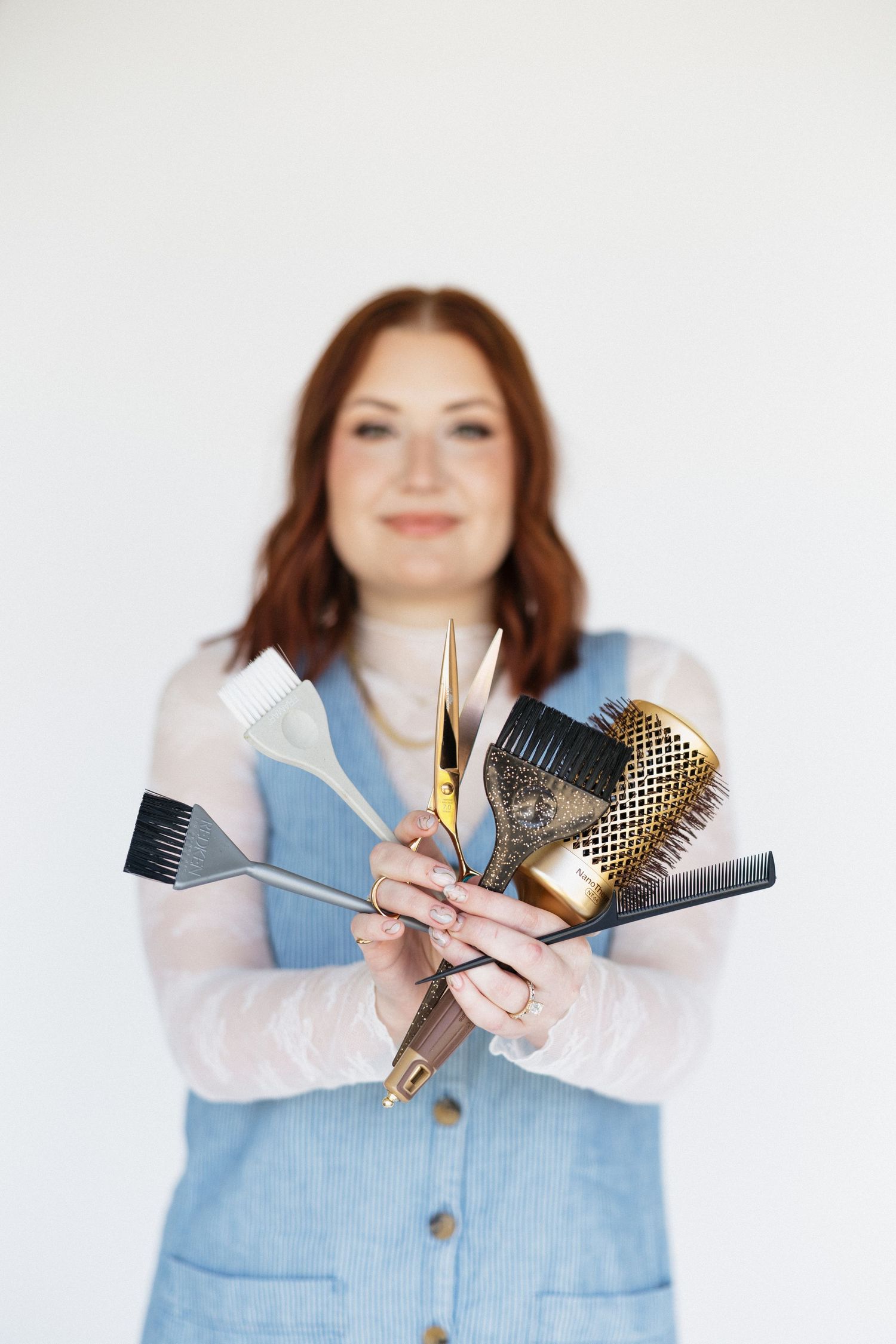 Collection of professional hair styling tools displayed in outstretched hands.