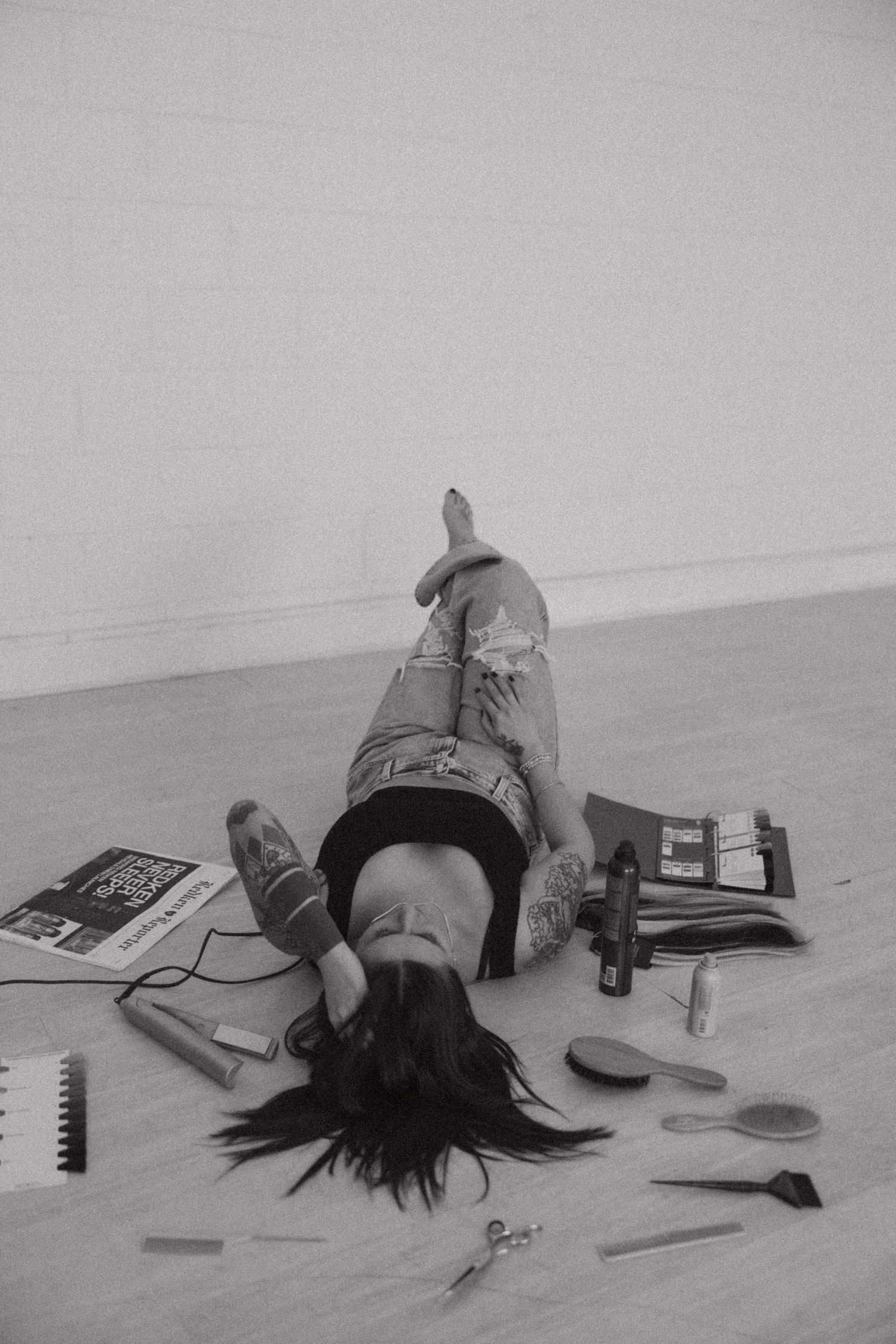 Black and white artistic setup with hairstyling tools and objects scattered on floor.