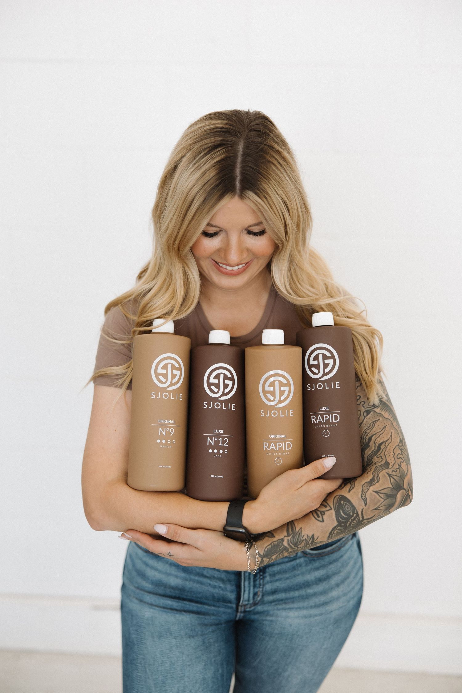 Marketing photo showing SJOLIE tanning product line in brown bottles.