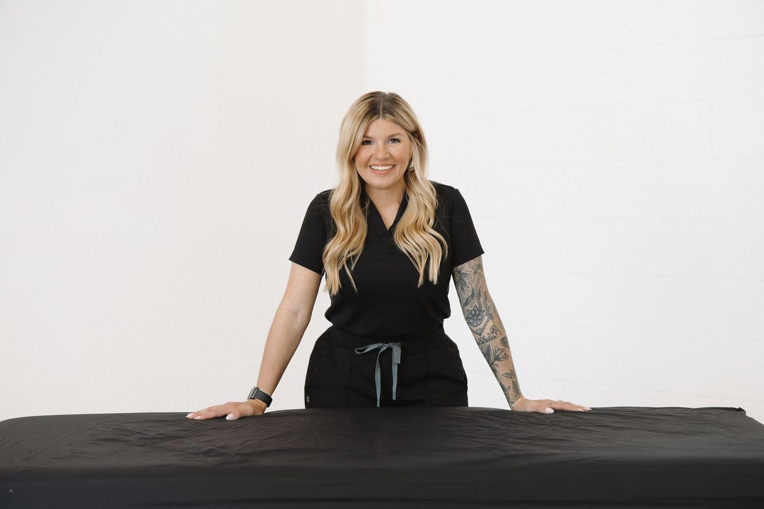 Professional studio shot of someone posing comfortably on black massage table.